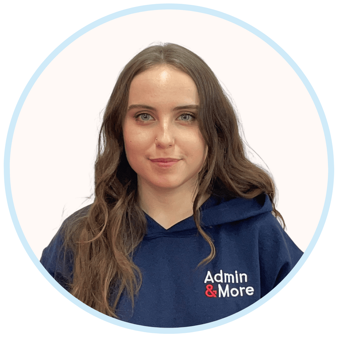 Woman with long brown wavy hair wearing a navy blue hoodie with 'Admin & More' logo is smiling lightly.