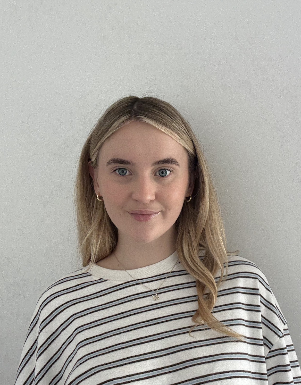 A smiling woman with long blonde hair wearing a striped top