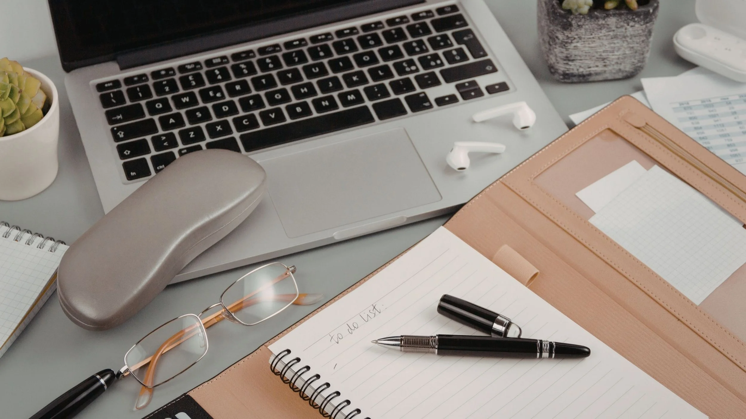 Tidy workspace with a laptop, notebook and stationery, representing organised and professional admin support.