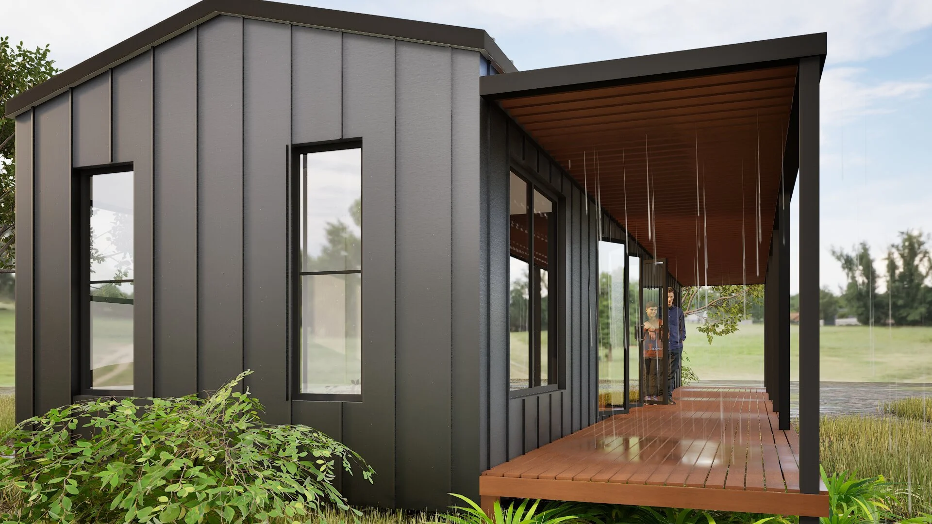 Modern house with metal siding, large windows, and a covered porch with wooden flooring. Two people are standing under the porch, surrounded by greenery and trees, with a landscape background.mid north coast modular homes scconstruction.online