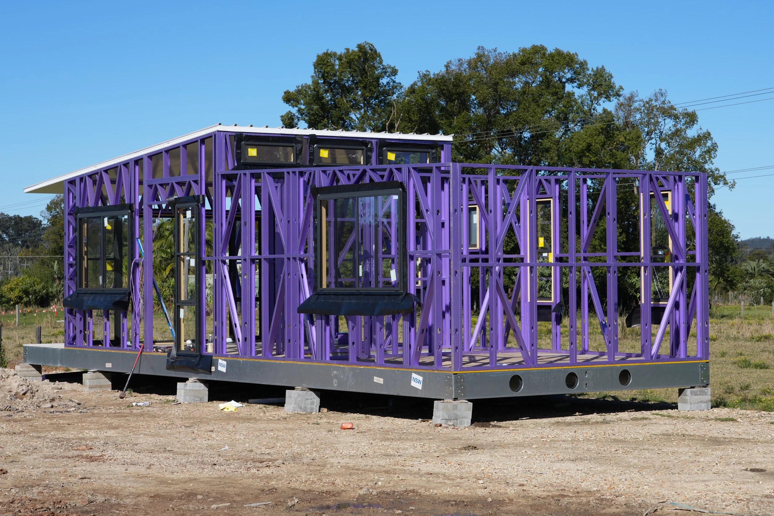 Frame of a house under construction with purple painted steel frame and windows installed made formid north coast modular homes scconstruction.online