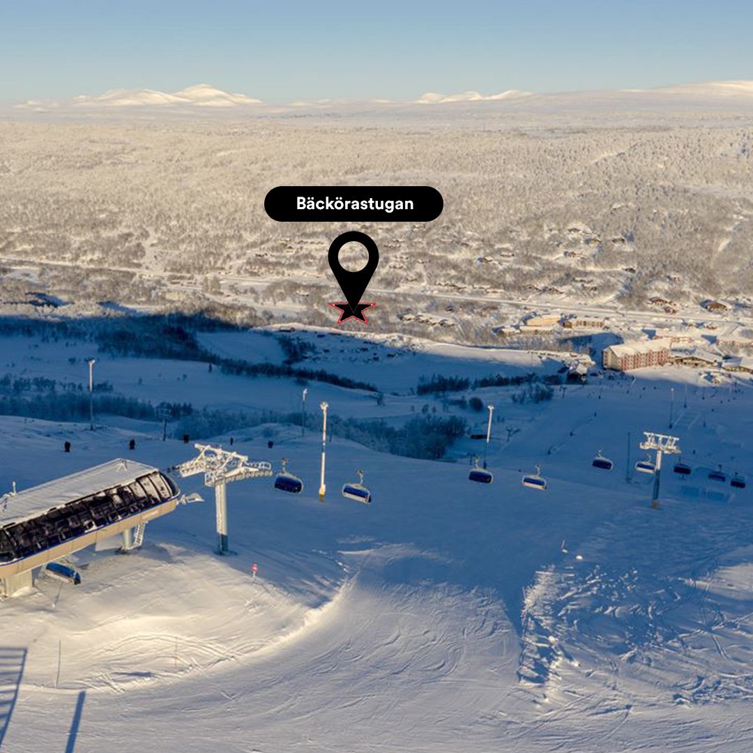 Snötäckta skidbackar och kabinlift med en byggnad i förgrunden. Det finns en markerad plats som heter Bäckörastugnan i bilden.