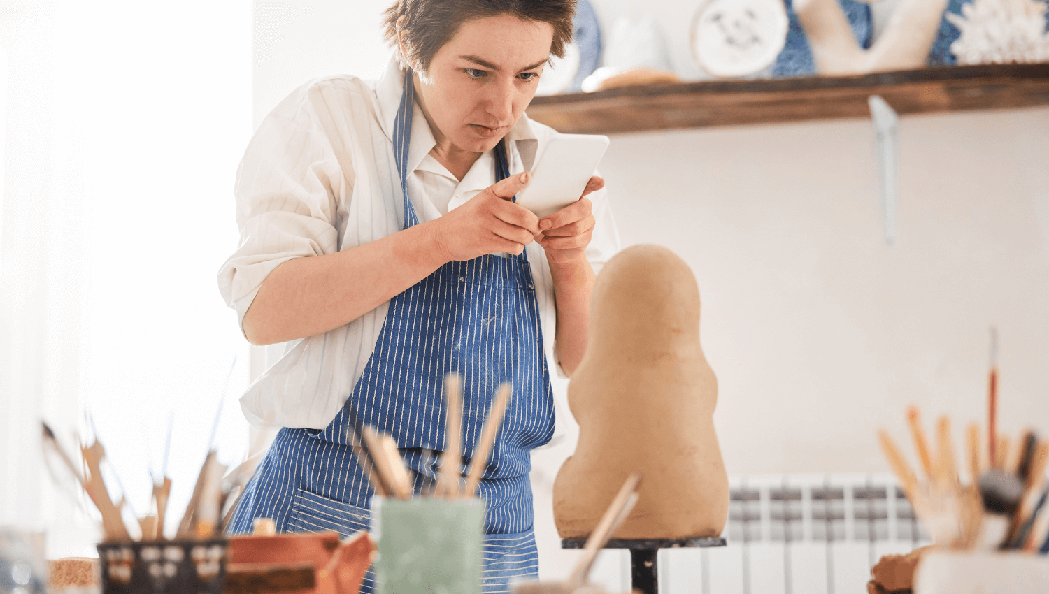 visual artist taking photos of work in studio on iphone