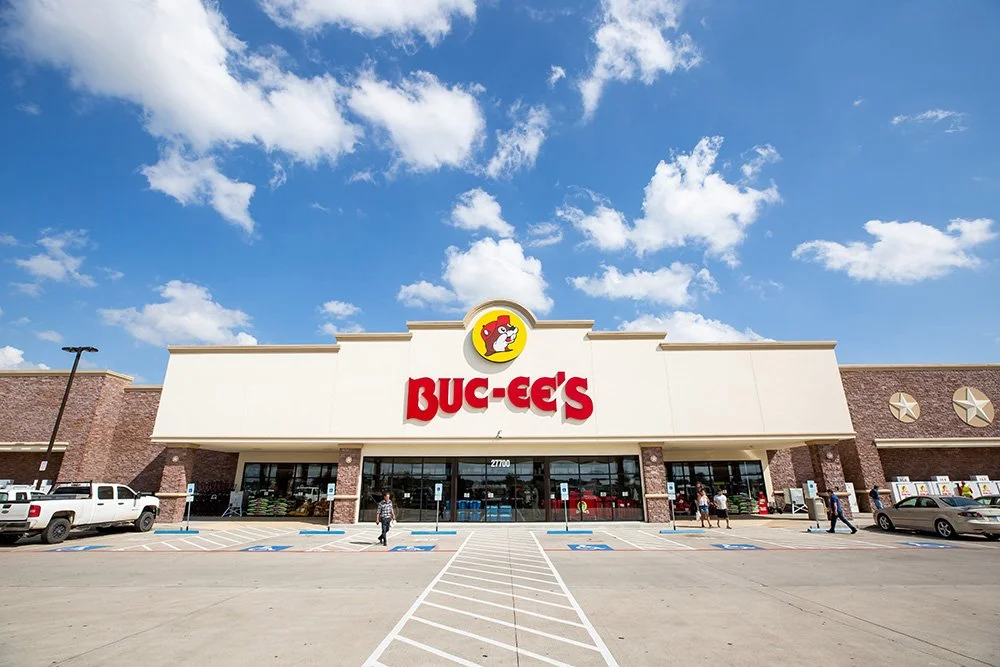 Front view of a Buc-ee's convenience store with a parking lot, under a partly cloudy sky.