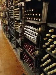 Wine bottles stored on black shelves in a wine shop aisle.