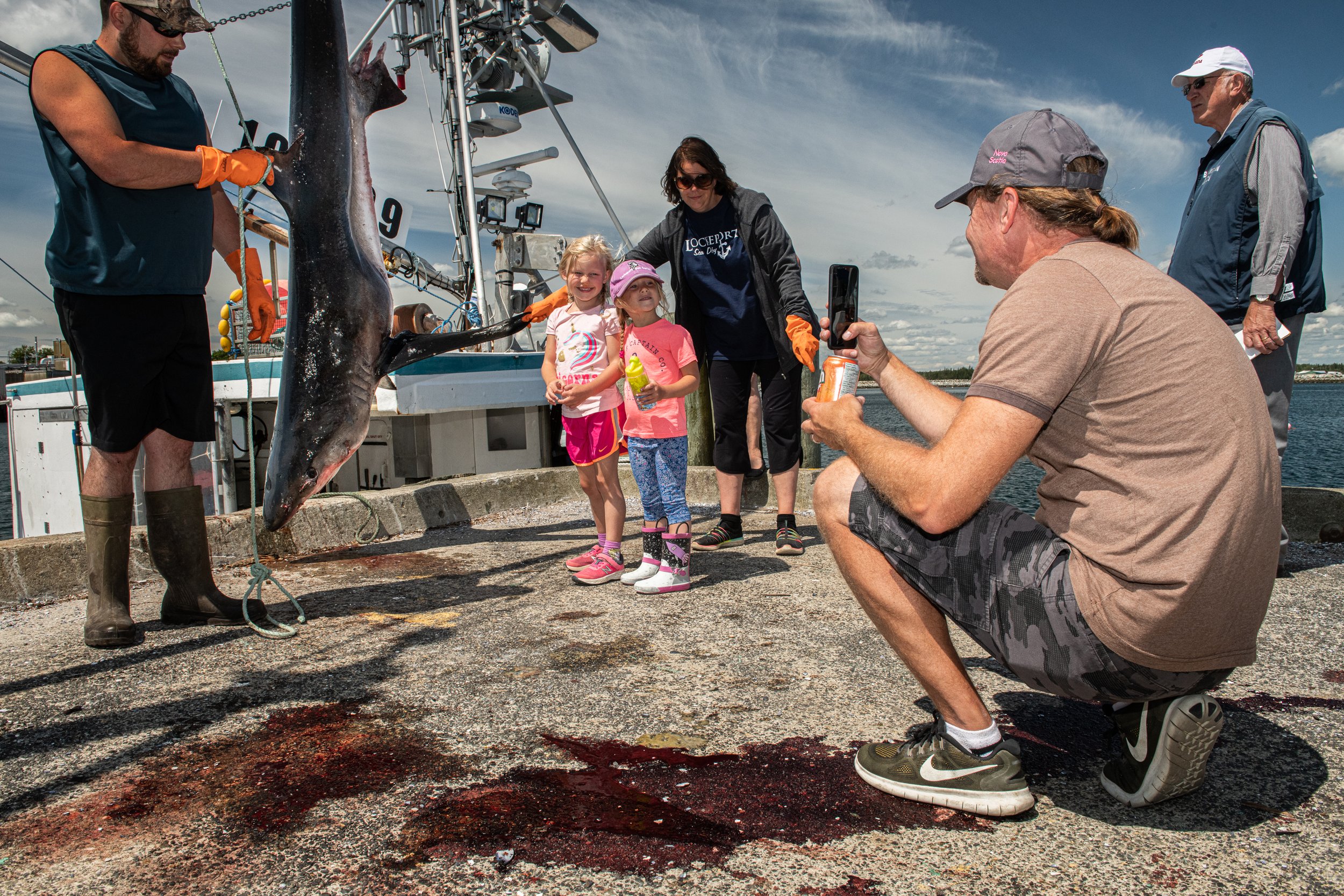 Young children stand with a dead blue shark that was killed in a recreational sport fishing competition in Nova Scotia, Canada.