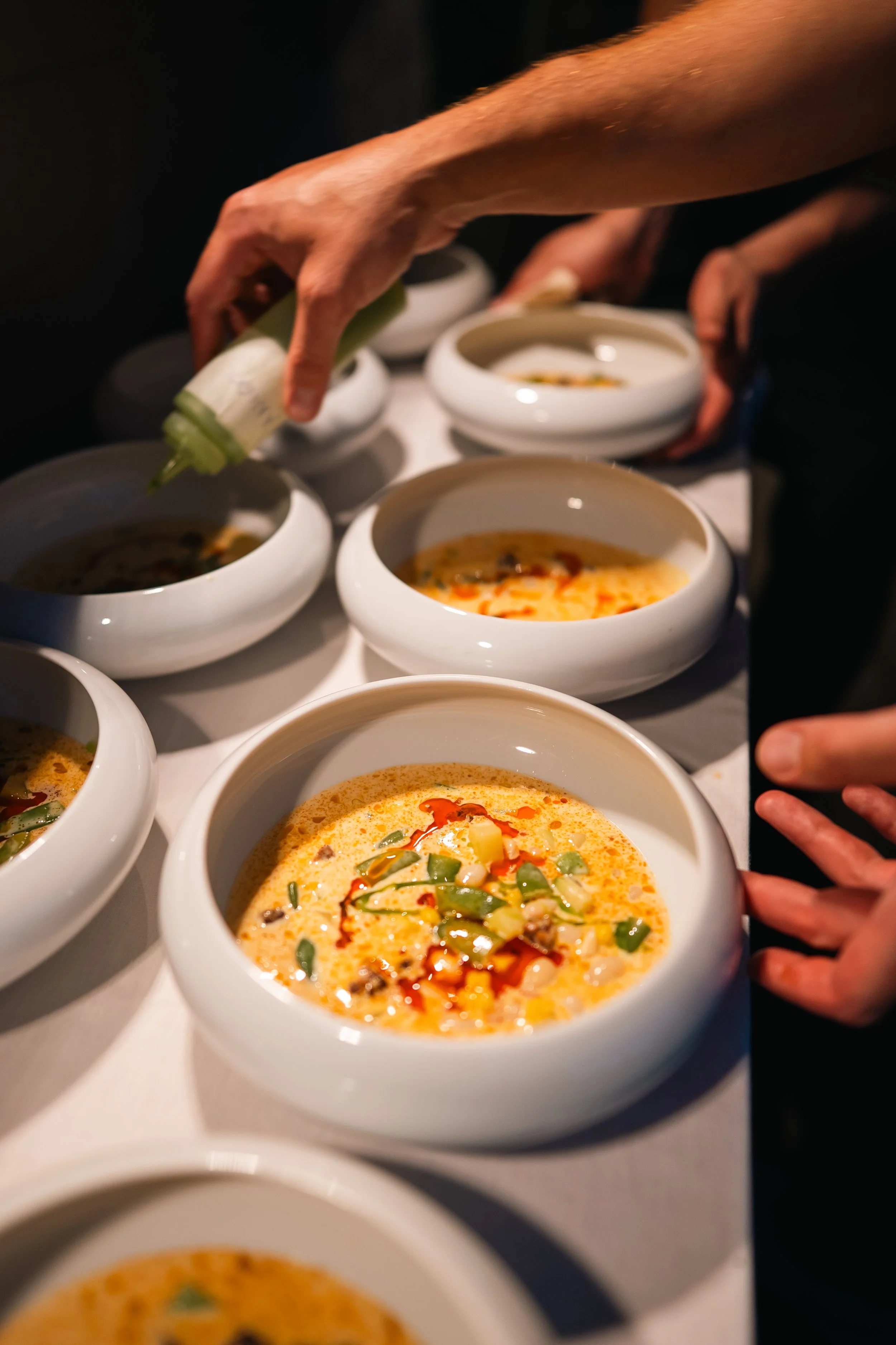 A terracotta bowl filled with rigattoni pasta with shrimps, and crumbled feta, garnished with herbs, on a wooden table. A white plate with a salad featuring lettuce and cherry tomatoes is served on the side.