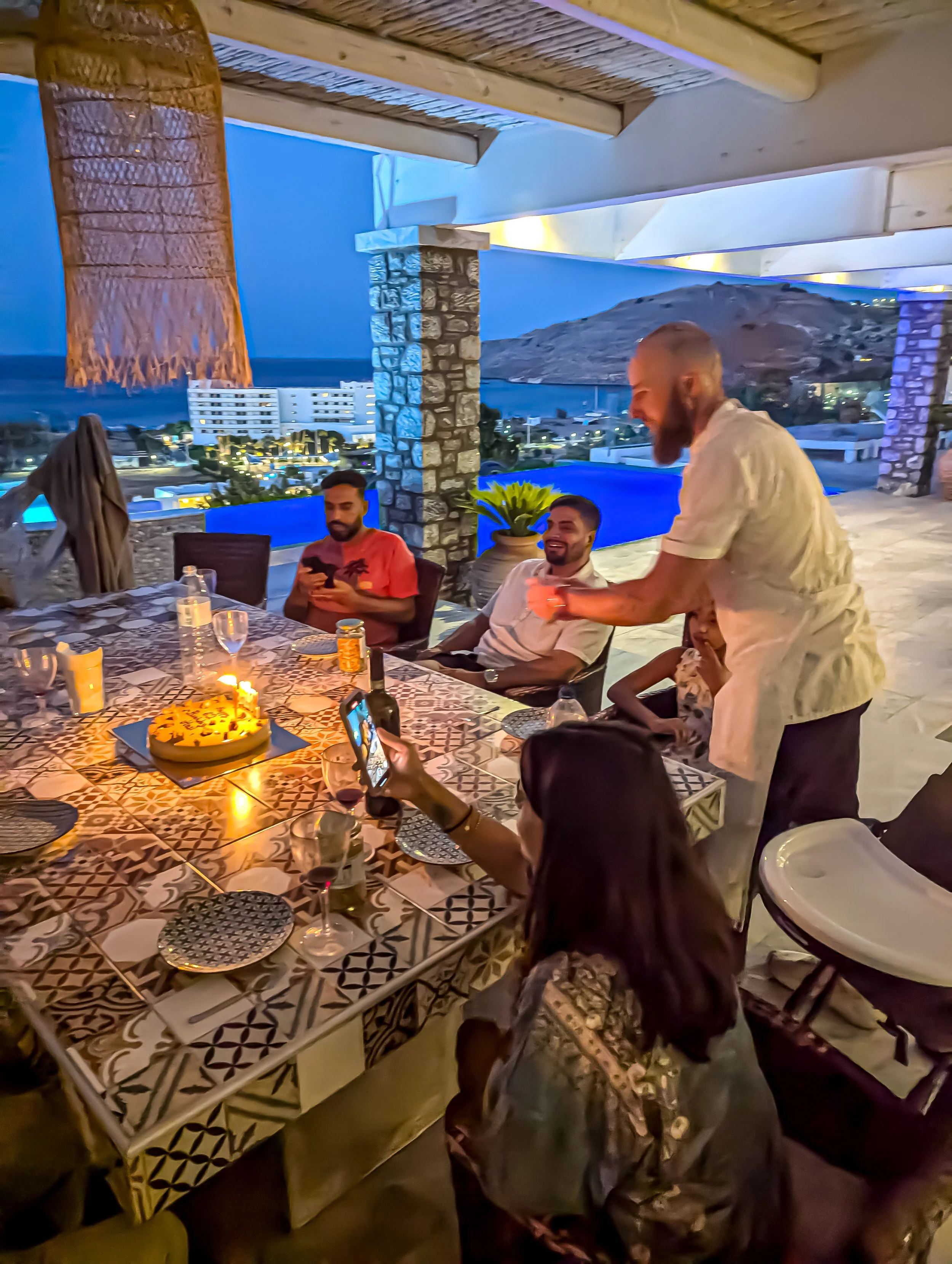 Homemade pieces of yoghurt cake served in a white-blue plate with a dollop of yoghurt  on a wooden surface with a lace and the whole cake on the back along with some lemons 