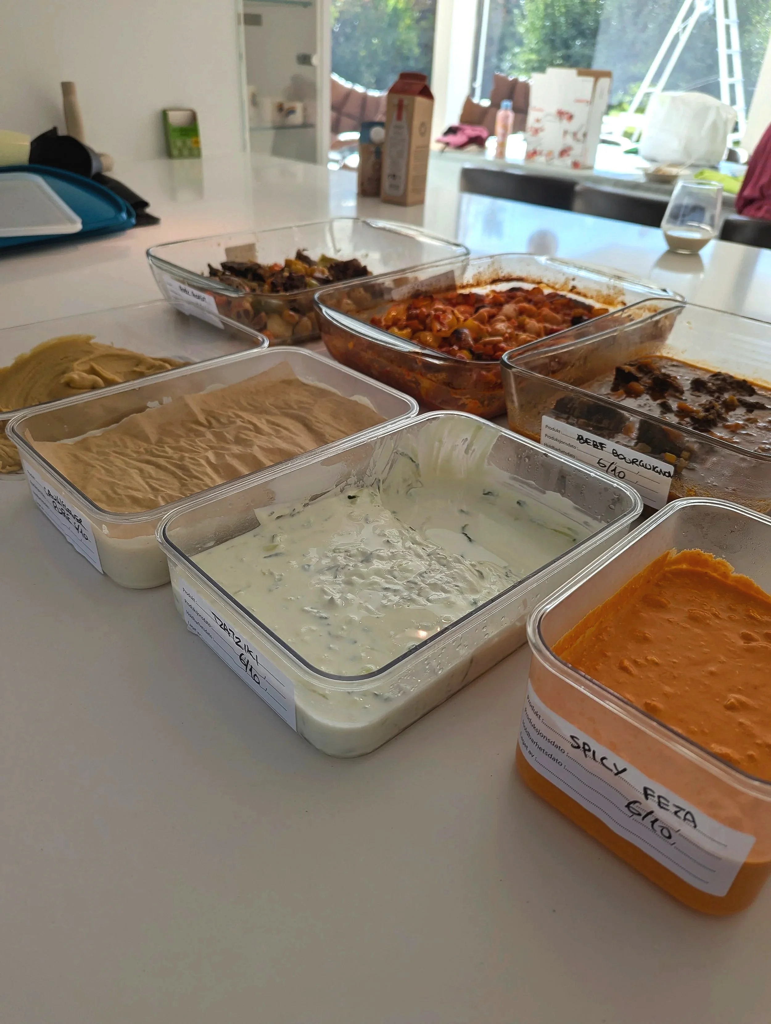 Large bowl of white bean salad with cucumbers, tomatoes, purple onions, and herbs. Set on a colorful crocheted tablecloth with a green napkin and two lemons in the background.