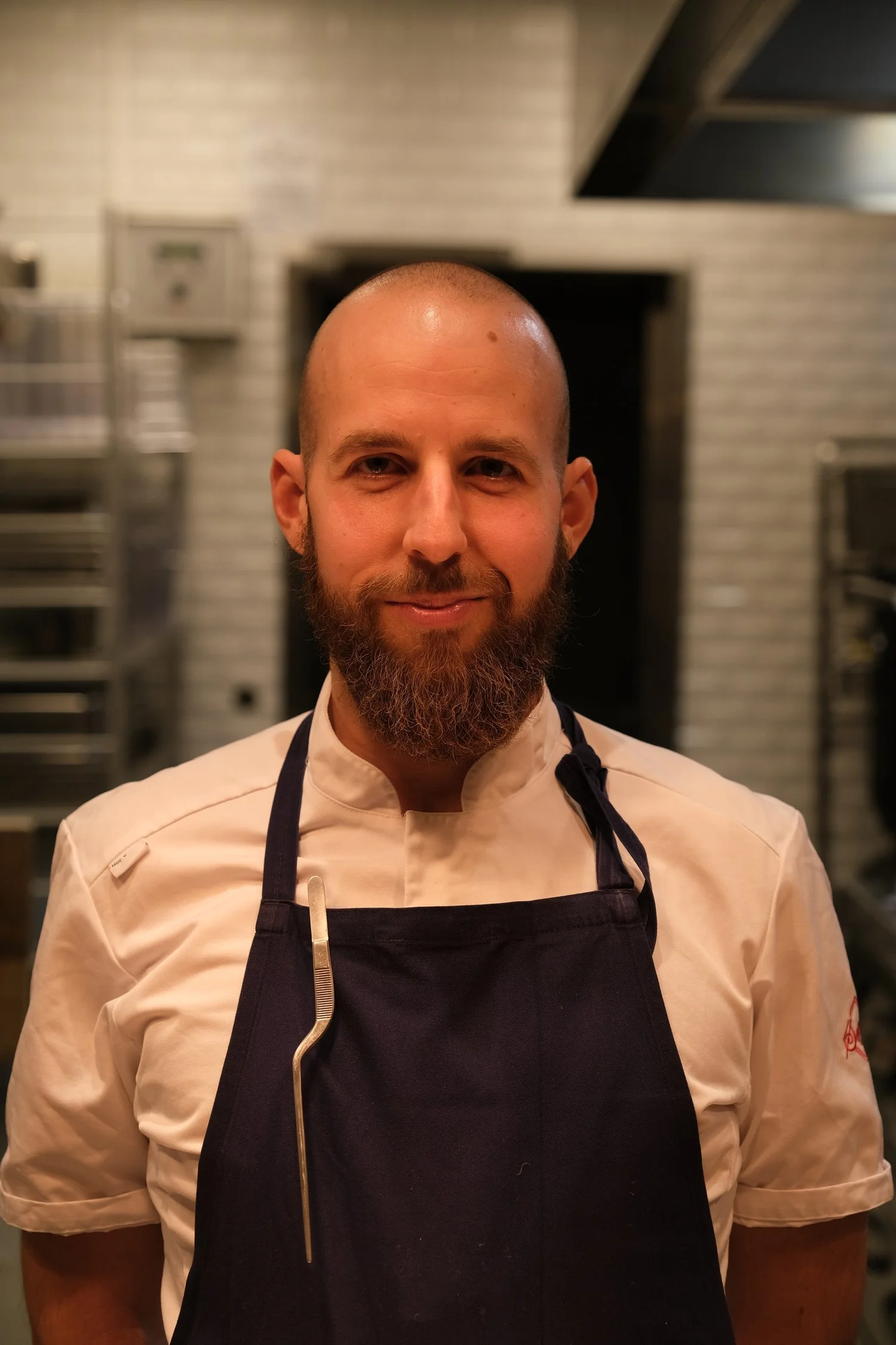 Chef Panagiotis Lenakis in a white chef jacket and navy apron in a professional kitchen