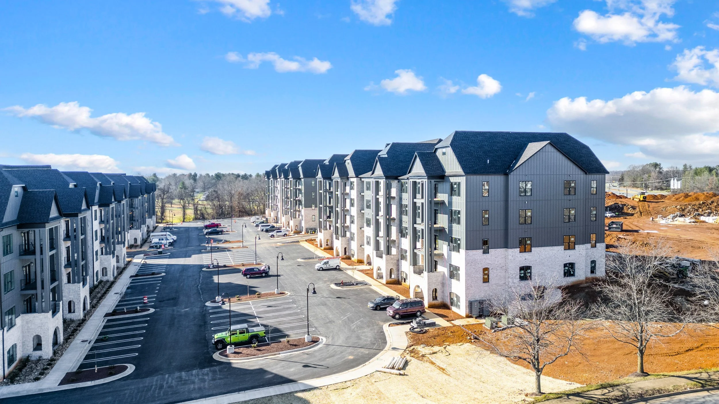 Colorized rendering of a residential complex with multiple apartment buildings, surrounded by greenery, shopping center, parking lots, and roads.