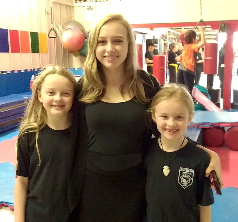 teen girl with arms around younger girls smiling
