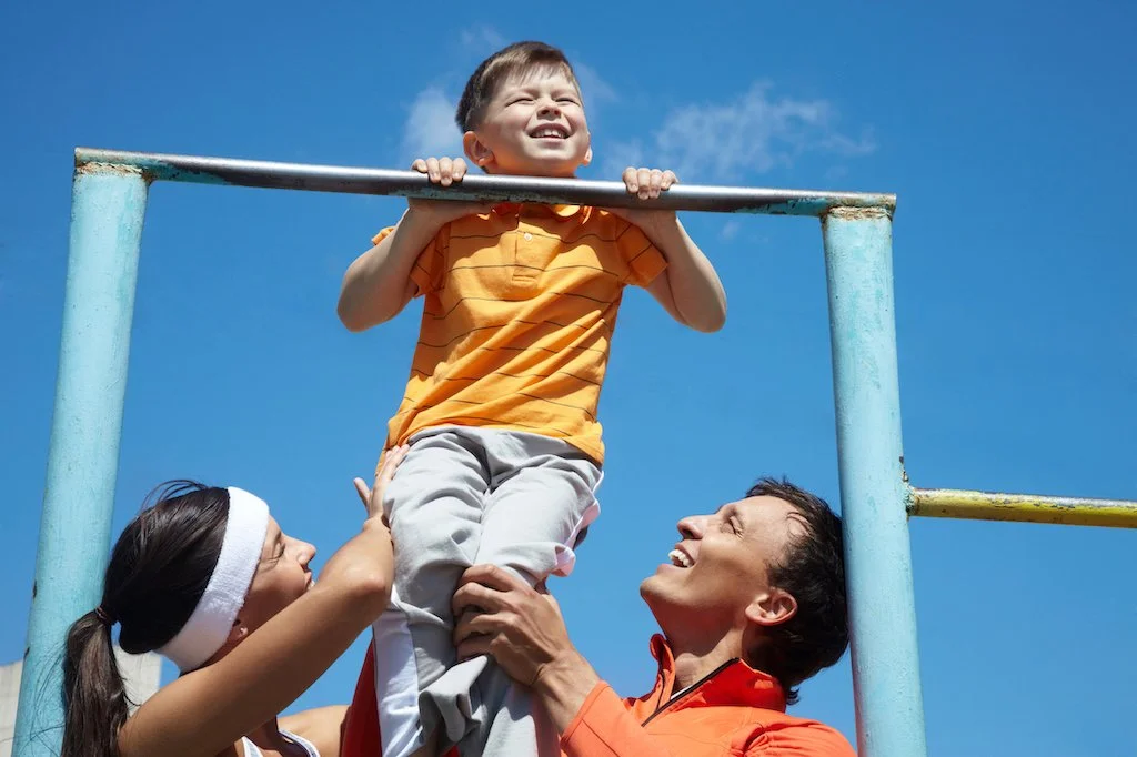 happy parents lifting son exercise chin up