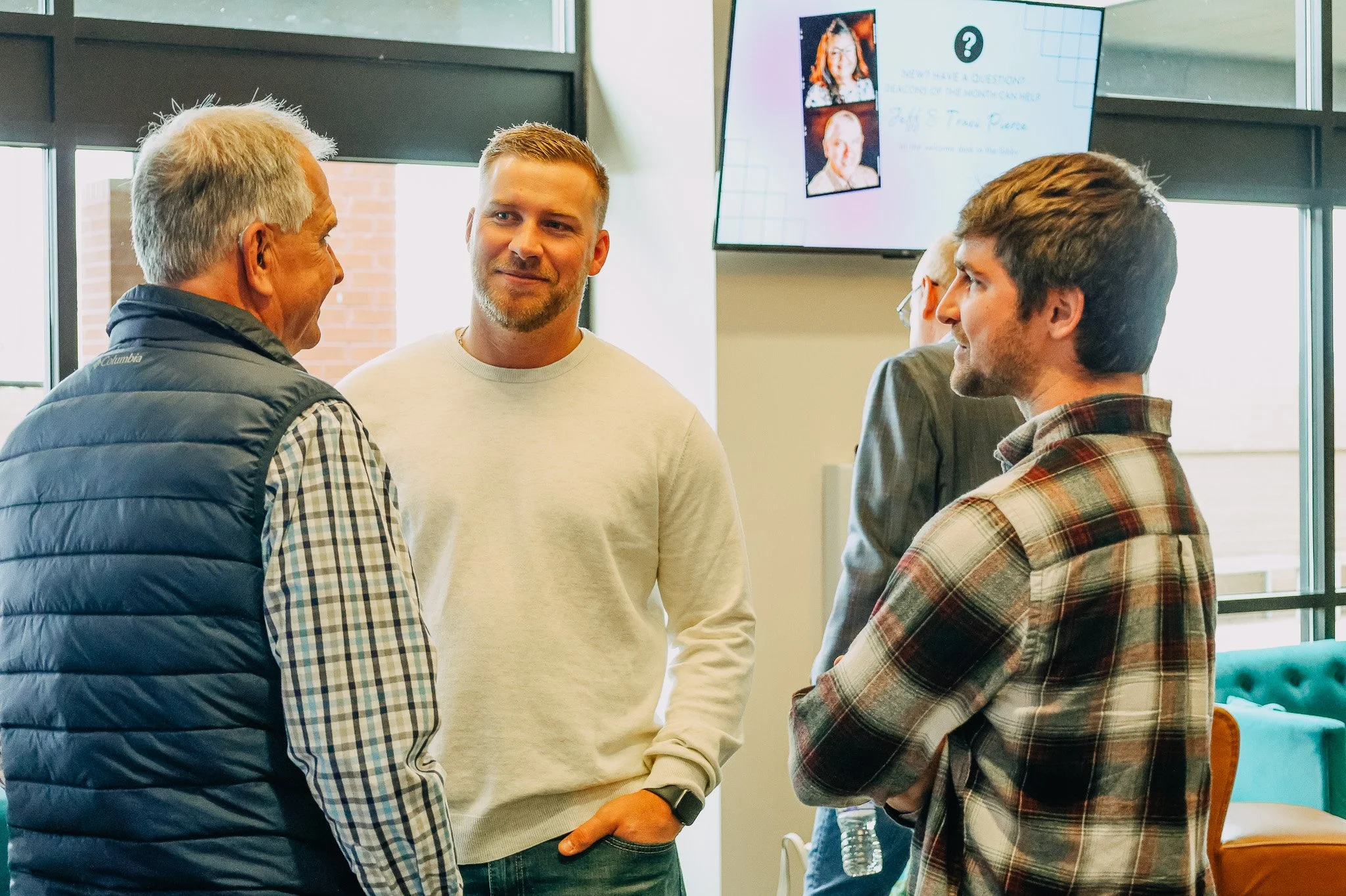 Four men engaging in conversation in the lobby at church.