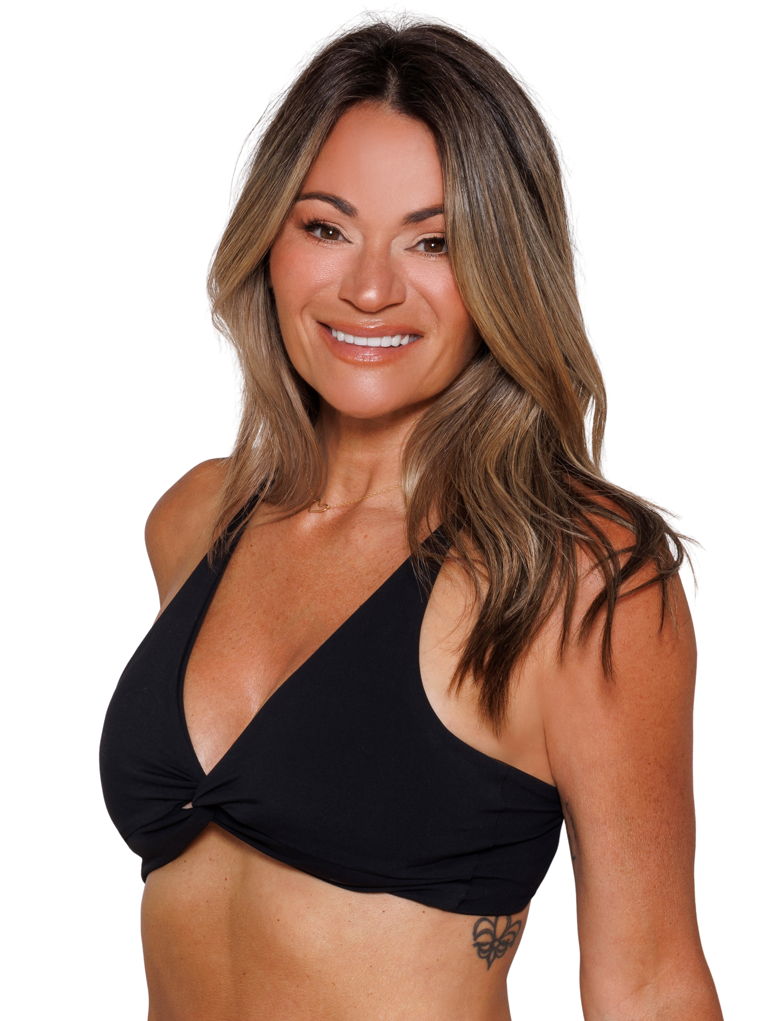 A woman with long brown hair, wearing a black sports bra, standing with one arm on her hip, against a black background.