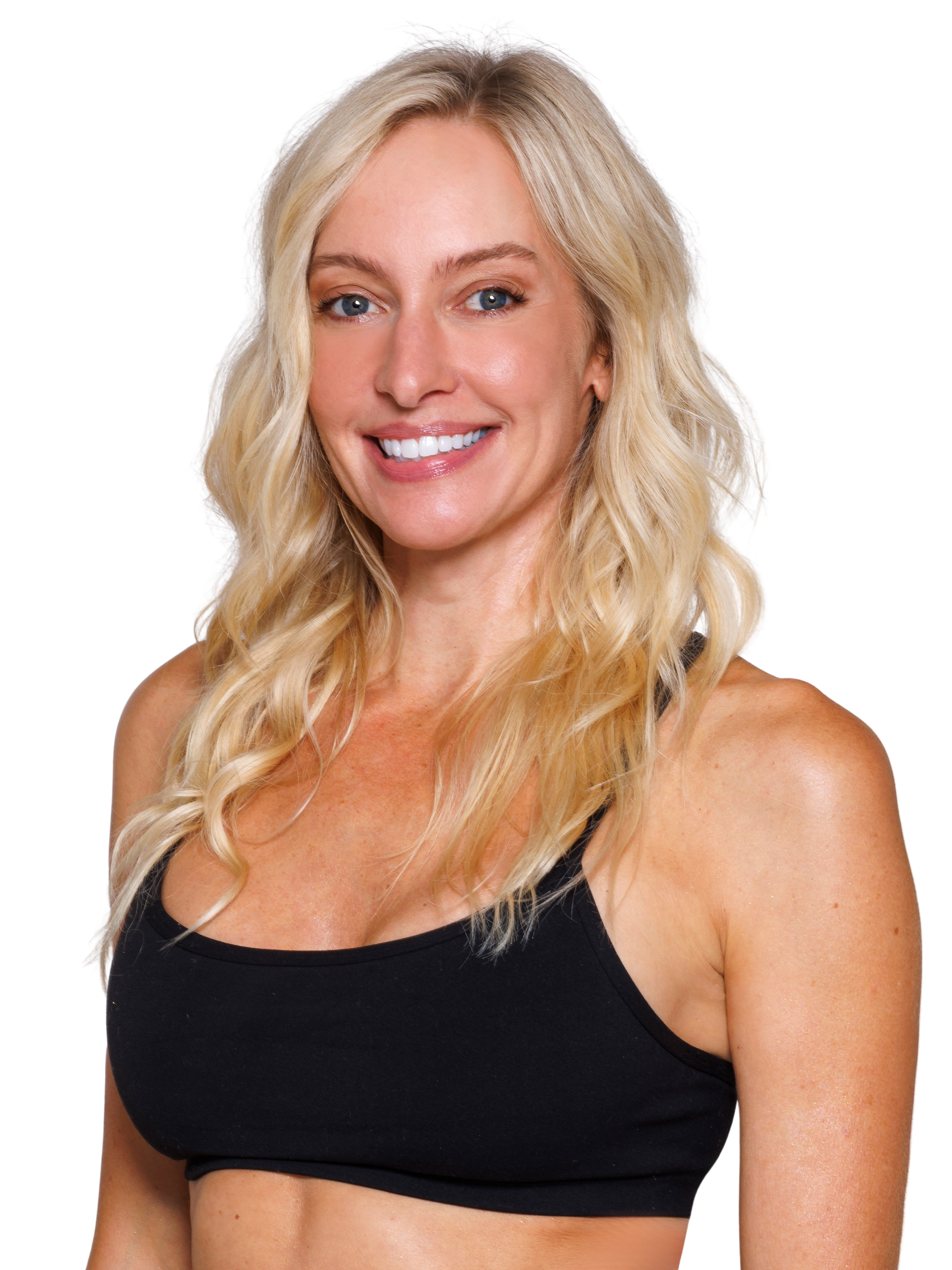 A smiling woman with wavy blonde hair, wearing a black sports bra and matching black bottoms, standing against a plain white background.