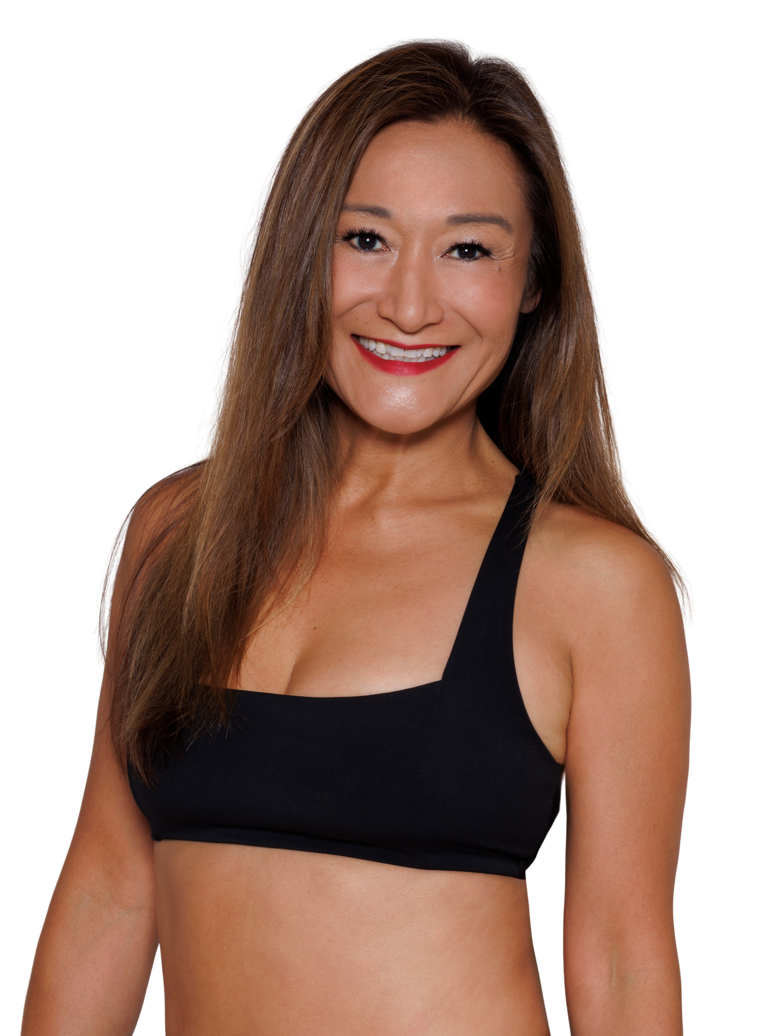 A woman with long dark hair smiling and standing with her hands on her hips, wearing a black sleeveless top with a circular design on the front.