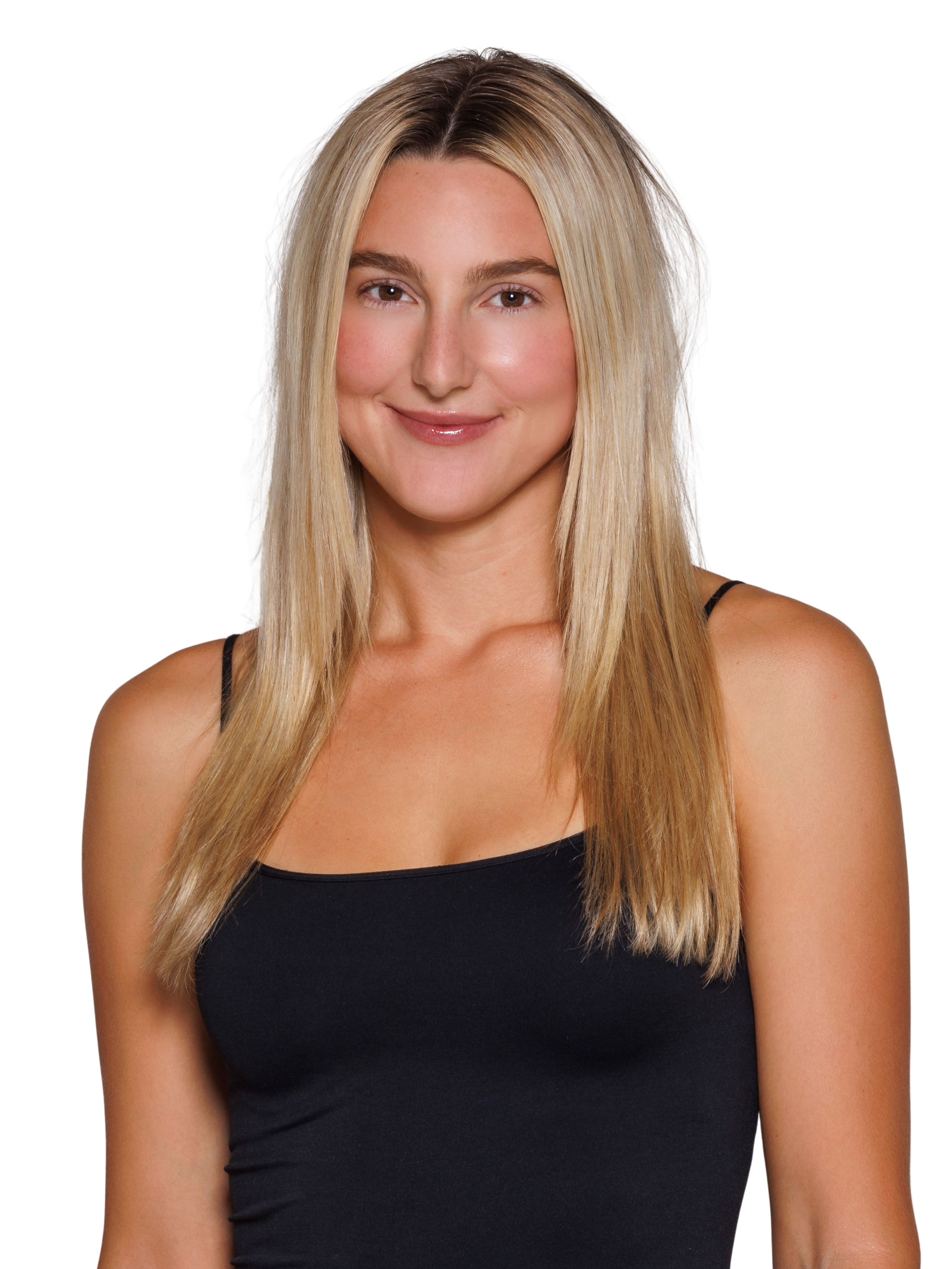 A woman with long blonde hair, wearing a black top, standing with one hand on her hip, smiling softly at the camera.