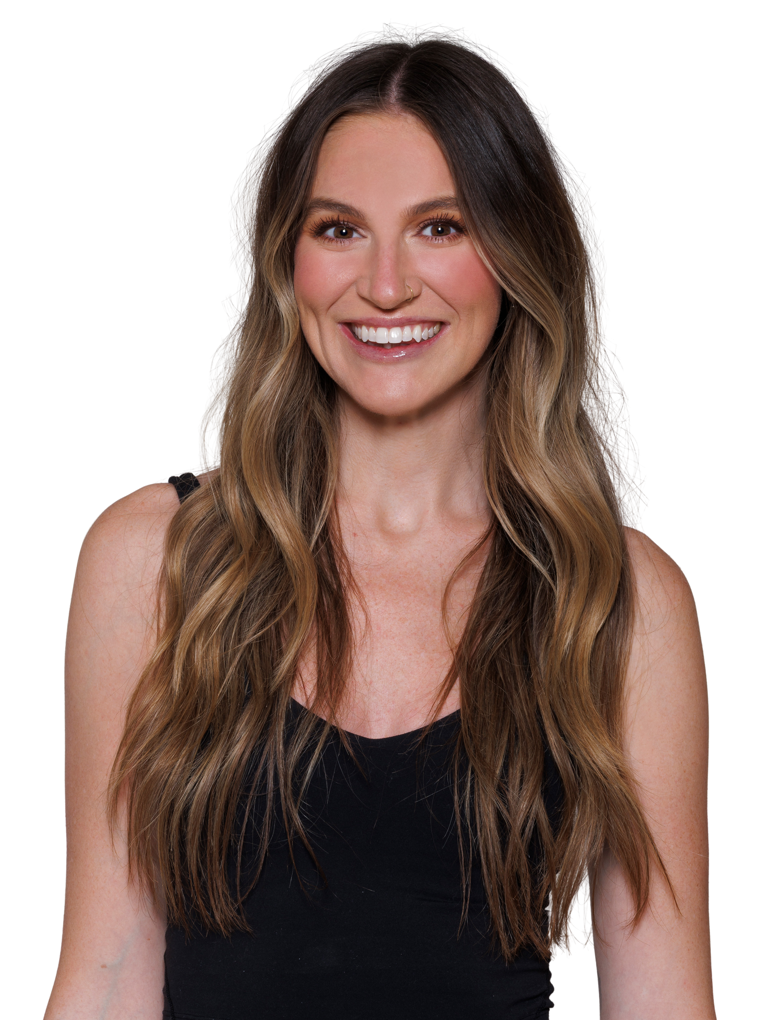 A woman with long wavy brown/blonde hair, wearing a black V-neck sleeveless top smiling at the camera