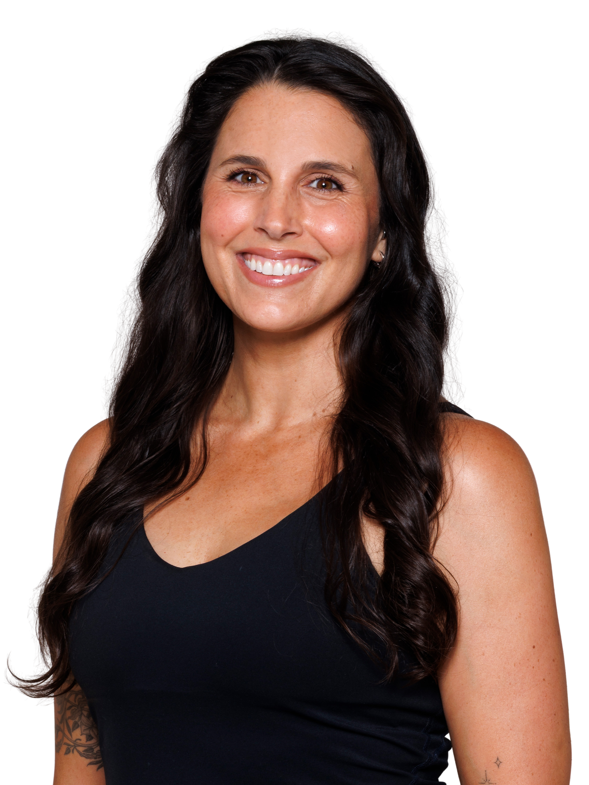 A woman with dark brown/black long hair that is curled, wearing a black V-neck tank top, smiling at the camera against a white background