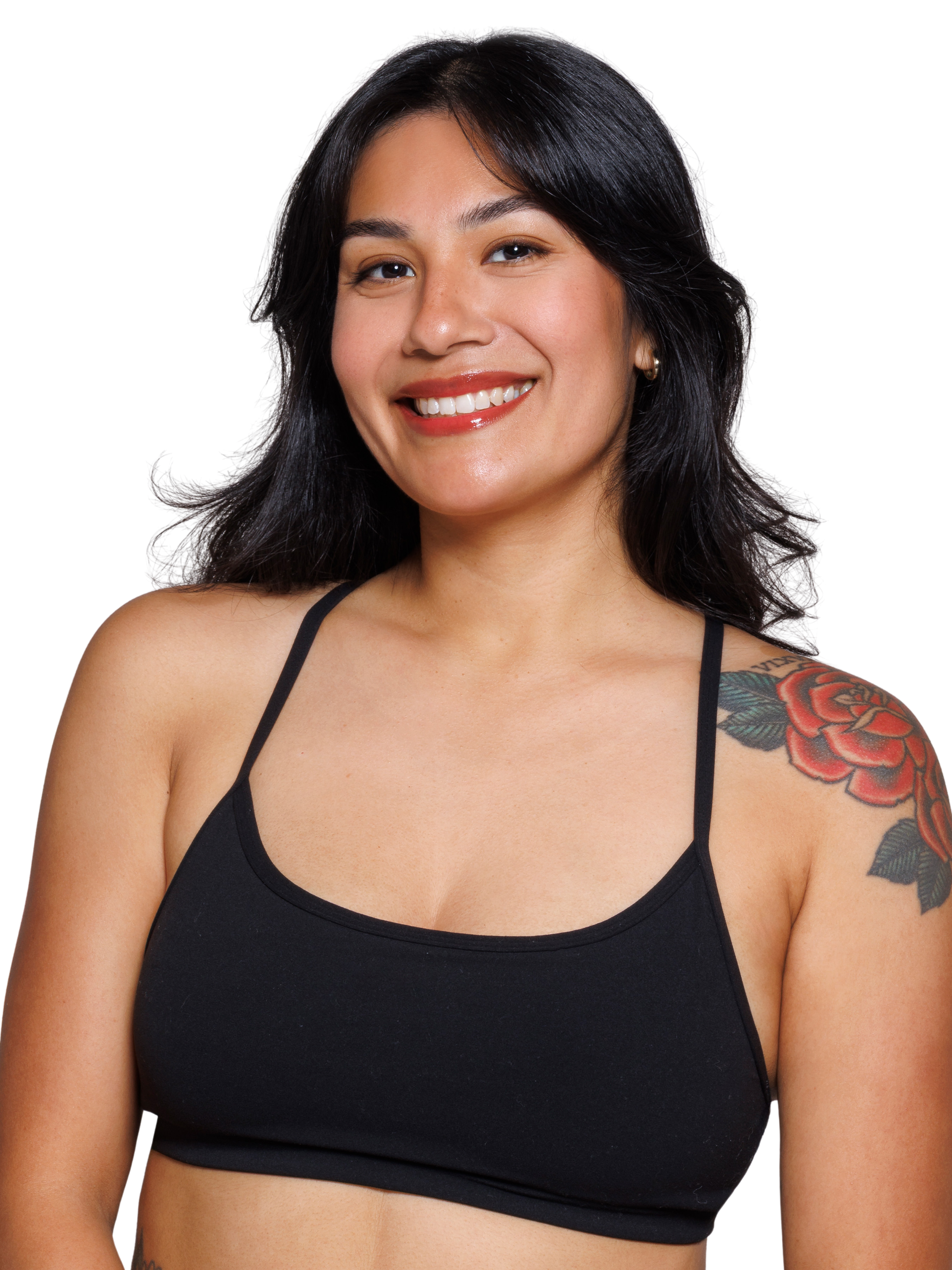 A woman with long wavy dark brown black hair, wearing a strappy black sports bra smiling at the camera. 