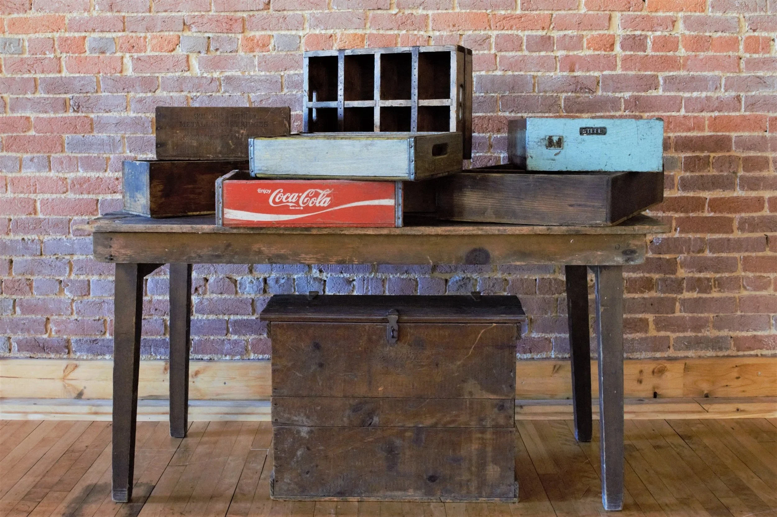 Wooden table with vintage crates and boxes against a brick wall.