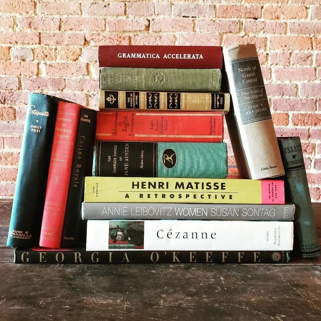 Stack of books on a wooden surface with a brick wall background.