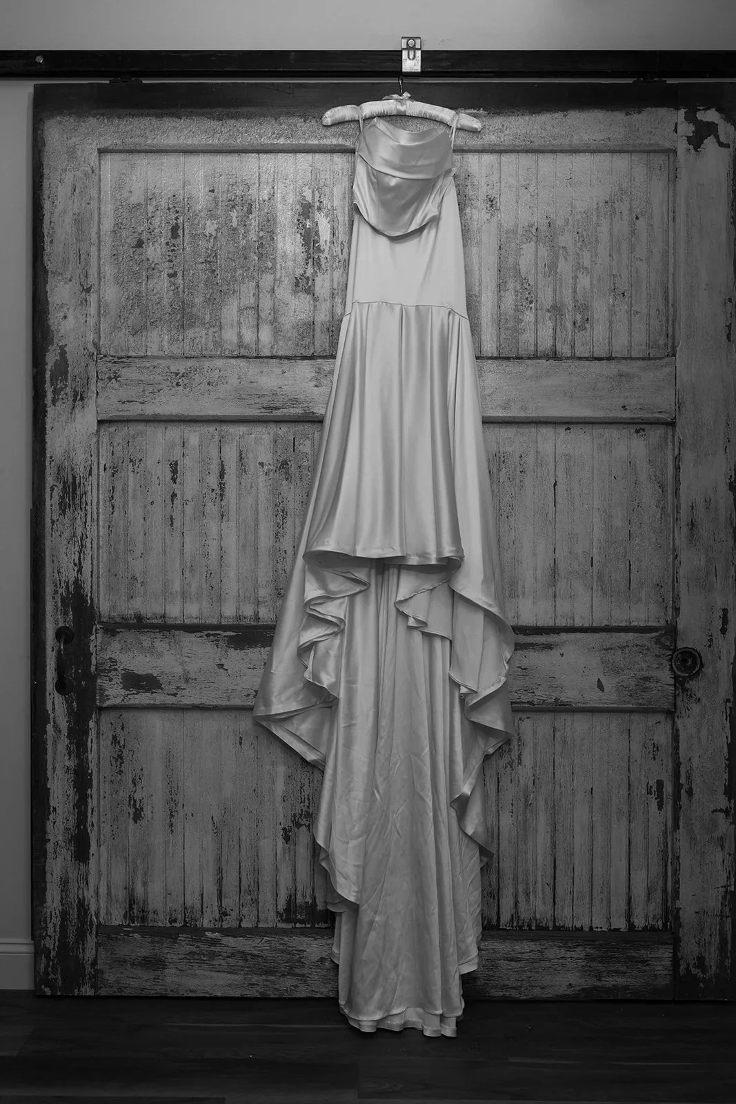 A wedding dress hanging on a wooden door.