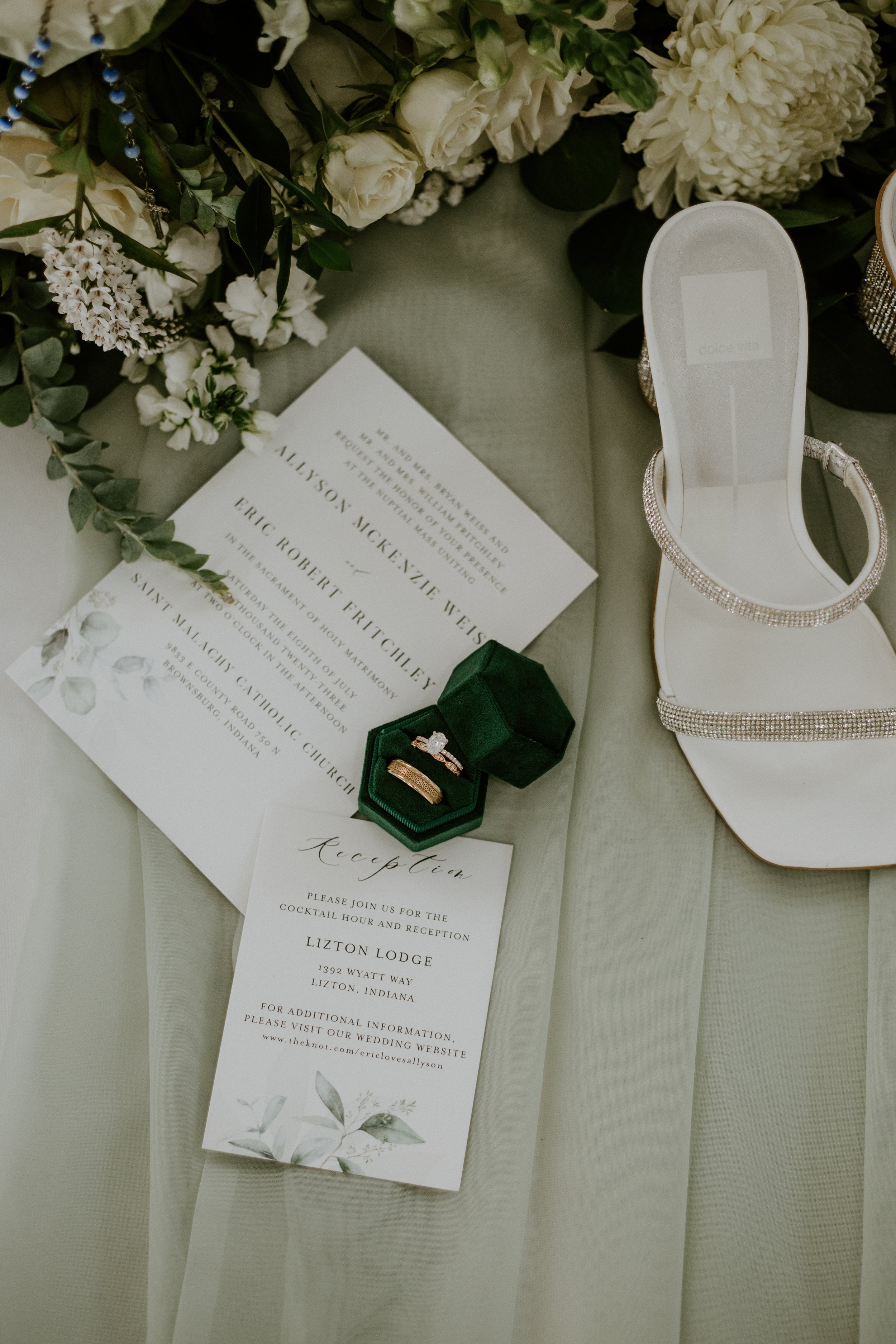 Lizton Lodge wedding invitation and bridal detail photo featuring wedding rings, white wedding shoes, and elegant floral arrangements.
