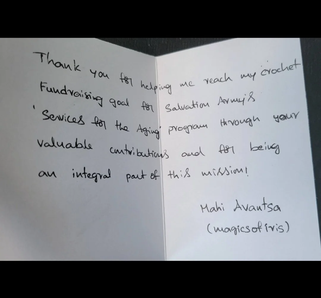 A handwritten thank you note on folded white paper expressing gratitude for help reaching a crochet fundraising goal for Salvation Army's services for the aging, signed by Mahi Avantsa.