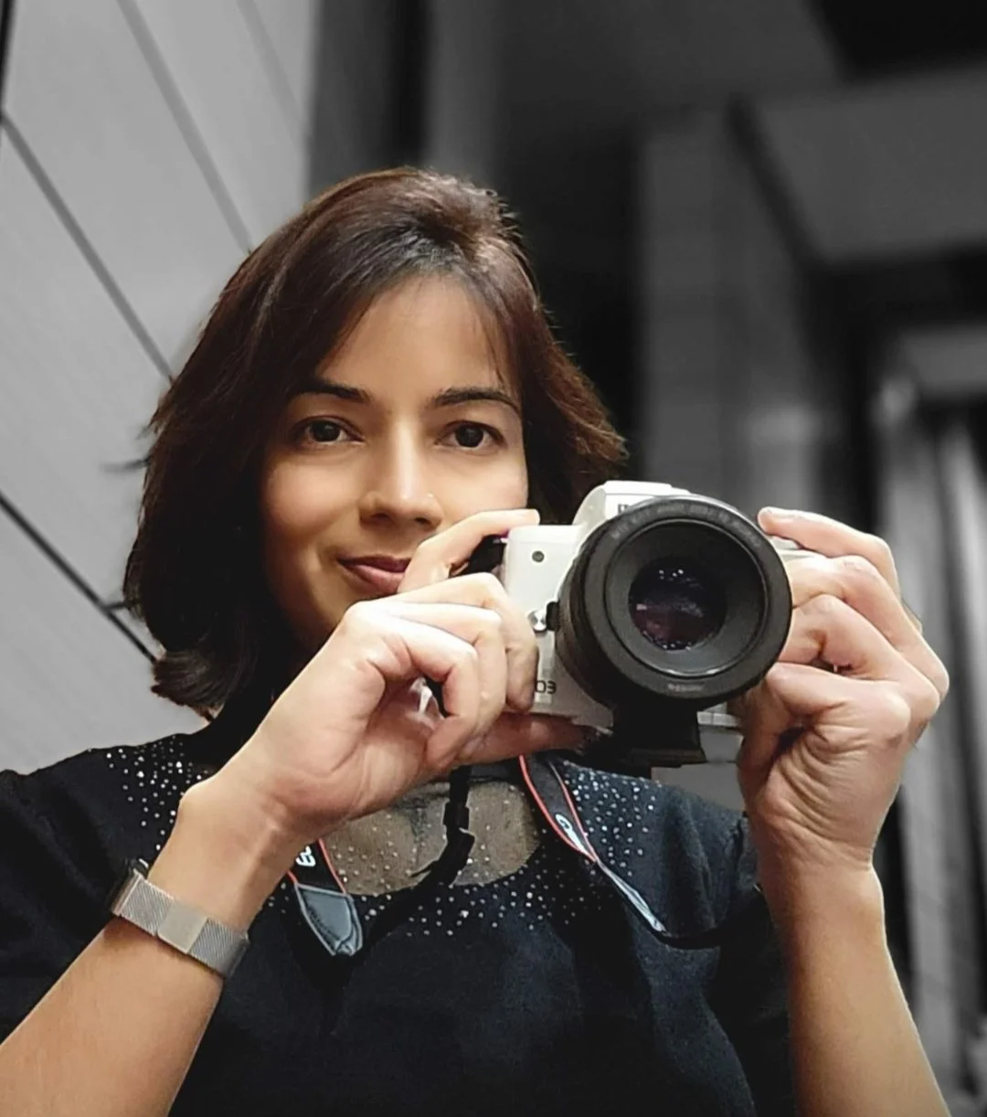 Woman taking a selfie with a camera, smiling and looking at the mirror.