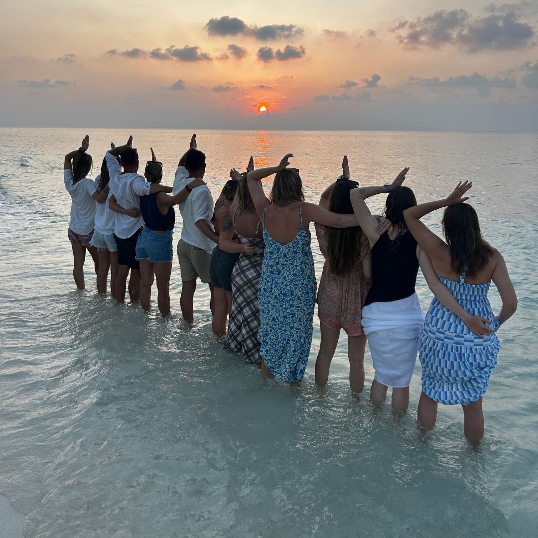 Group of freedivers by the beach doing the shark fins pose