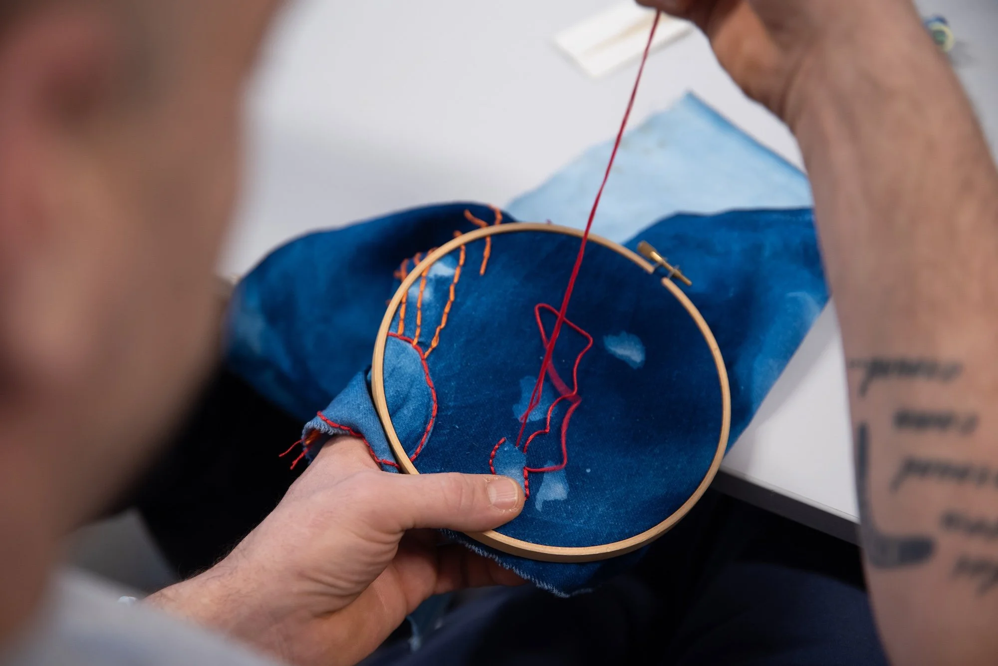 Sceneteppe til Ringerike fengsel, avdeling Ullersmo, i samarbeid med en gruppe innsatte. Teknikk og materiale: Cyanotype på tekstilbiter i bomull, lin, silke og ull, broderi i ull, silke og bomull, applikert på kraftig bomullstekstil. Håndsøm. Fôret 