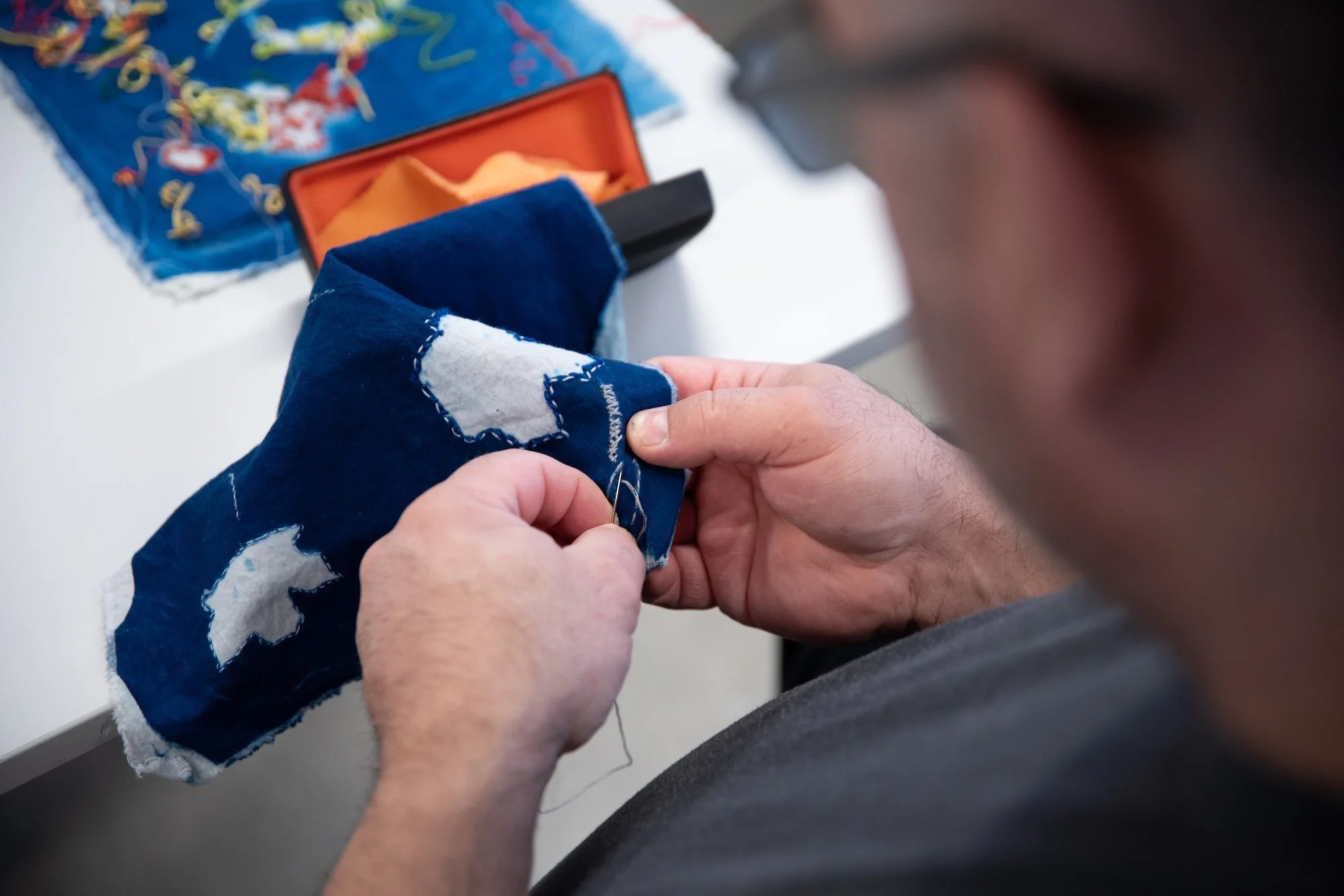 Sceneteppe til Ringerike fengsel, avdeling Ullersmo, i samarbeid med en gruppe innsatte. Teknikk og materiale: Cyanotype på tekstilbiter i bomull, lin, silke og ull, broderi i ull, silke og bomull, applikert på kraftig bomullstekstil. Håndsøm. Fôret 