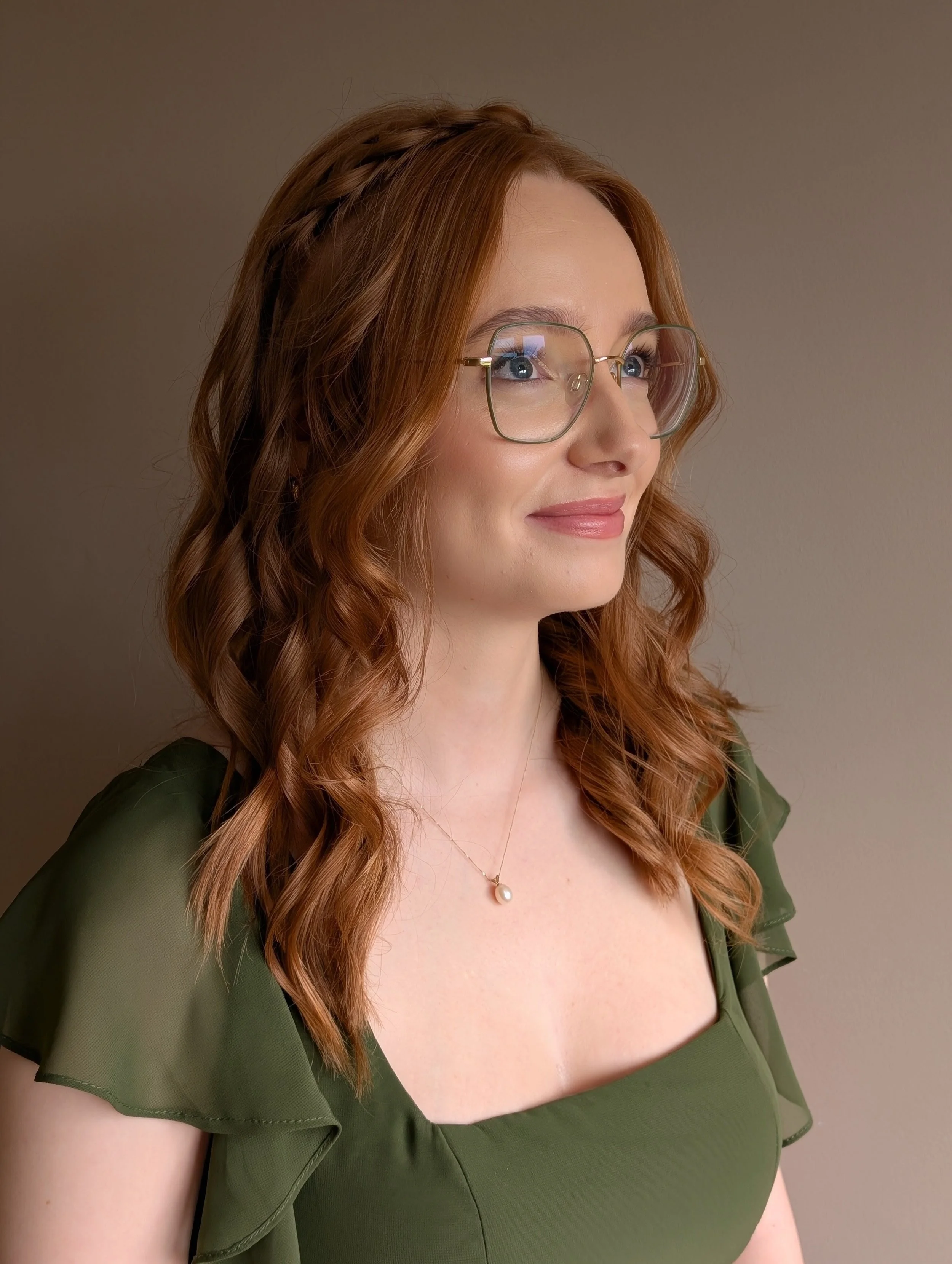 A blonde woman with beautiful 1930s hair stands side on. She has her hair fingerwaved and is wearing red lipstick.