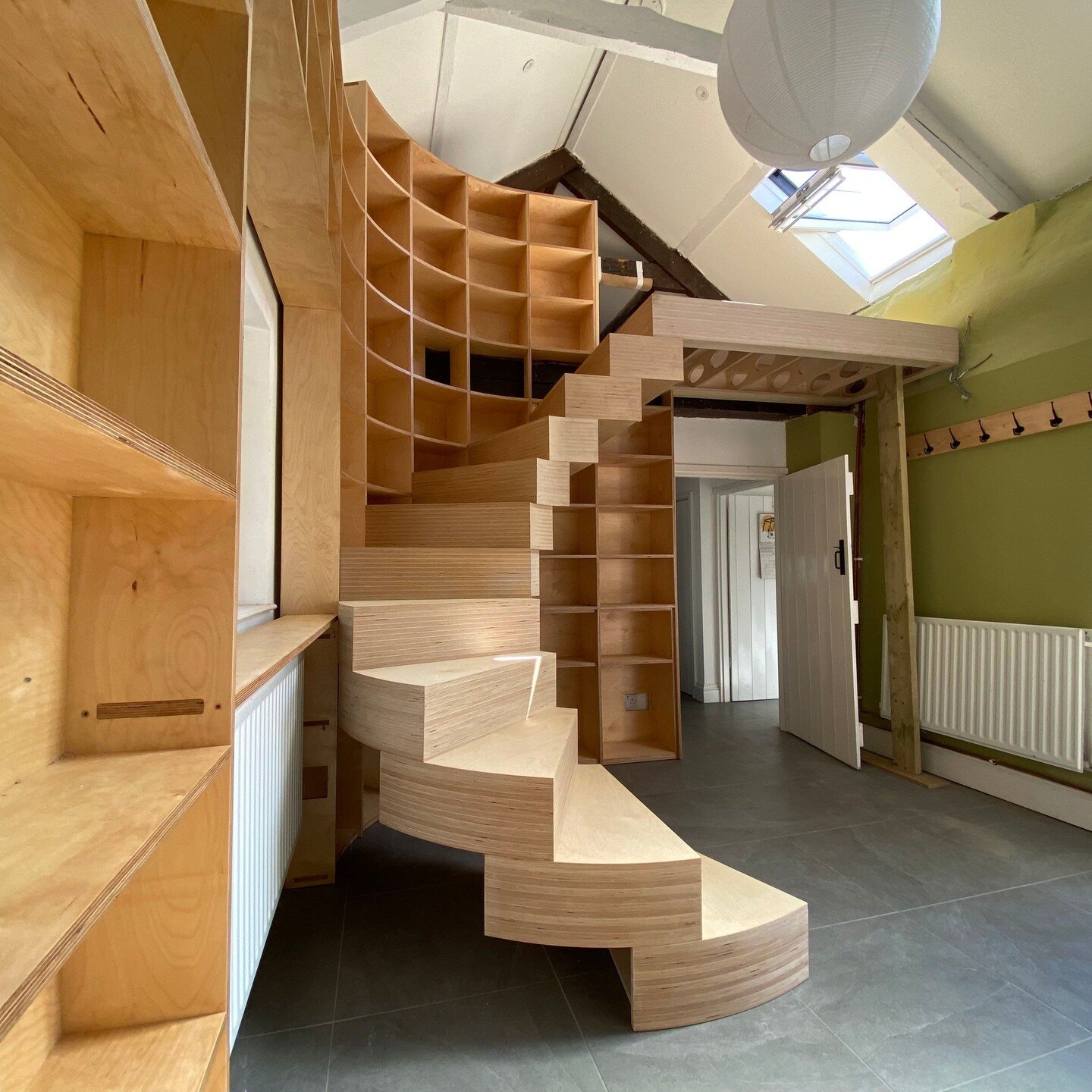 A birch plywood spiral staircase supported and cantilevered from a curved corner bookshelf.
@ammonite.designs painstakingly measured the space and designed the stairs to tie into the existing walls while remaining a free-standing structure inside a 3
