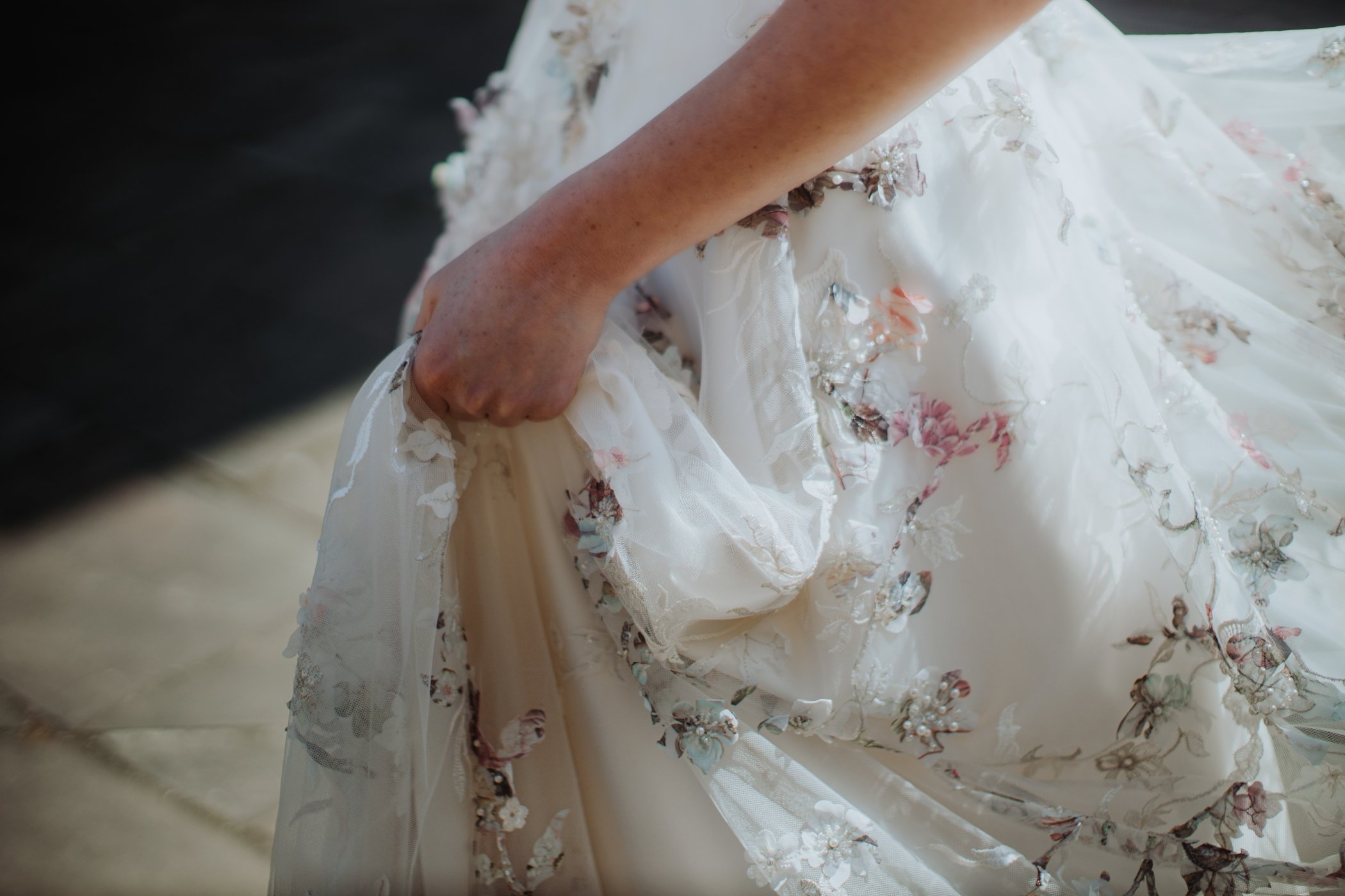 Close up of bride holding up floral dress
