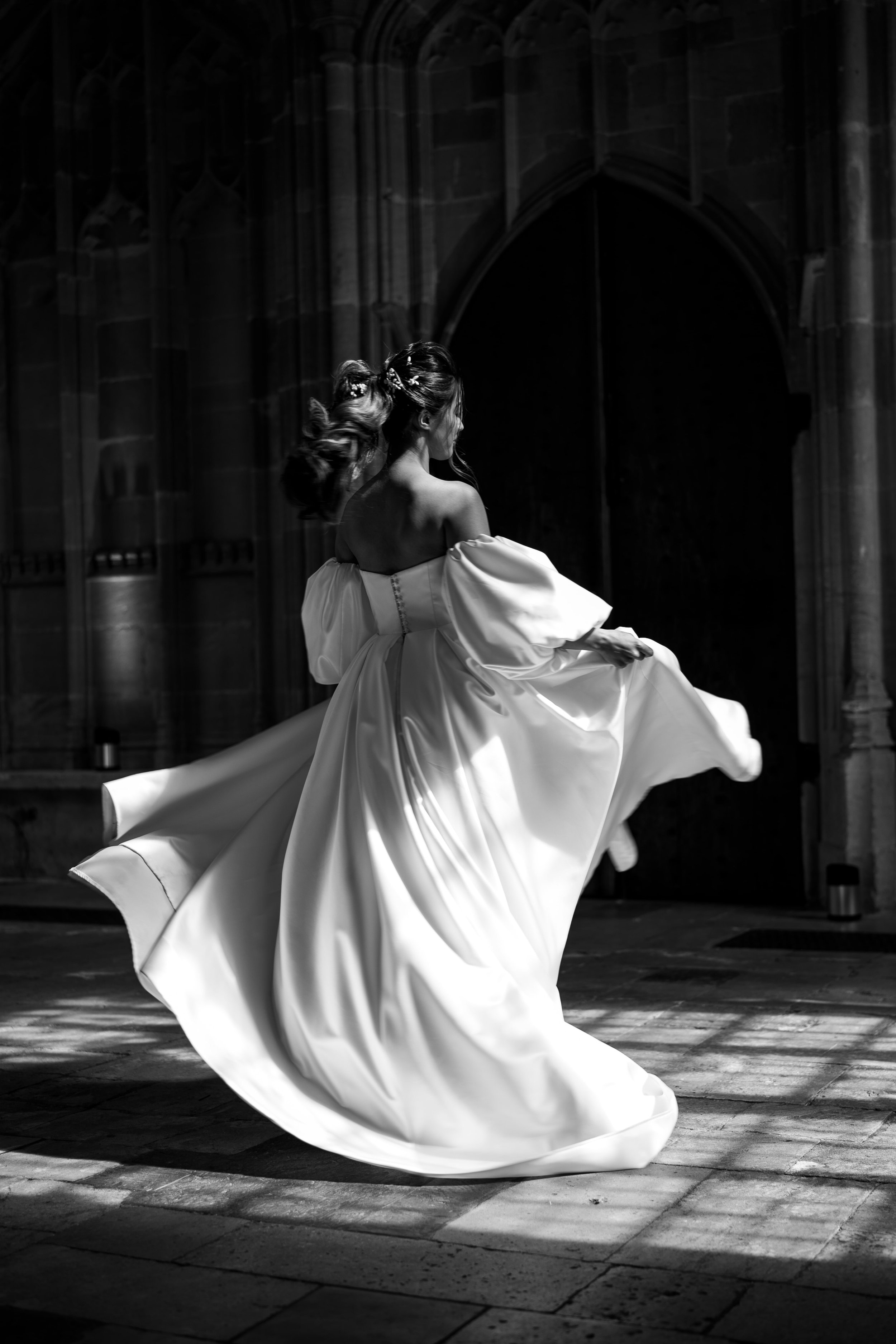 Black and white image of bride twirling her dress