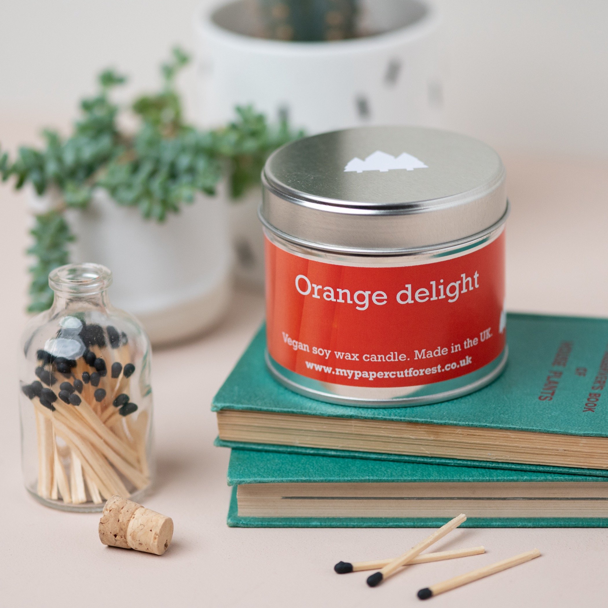 Citrus orange candle on top of books by My Papercut Forest