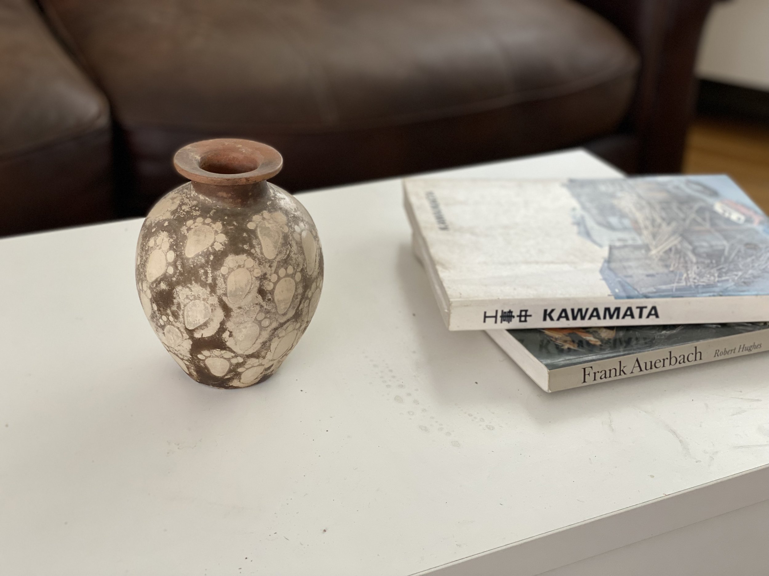 Ceramic vase with speckled pattern on white table beside two art books