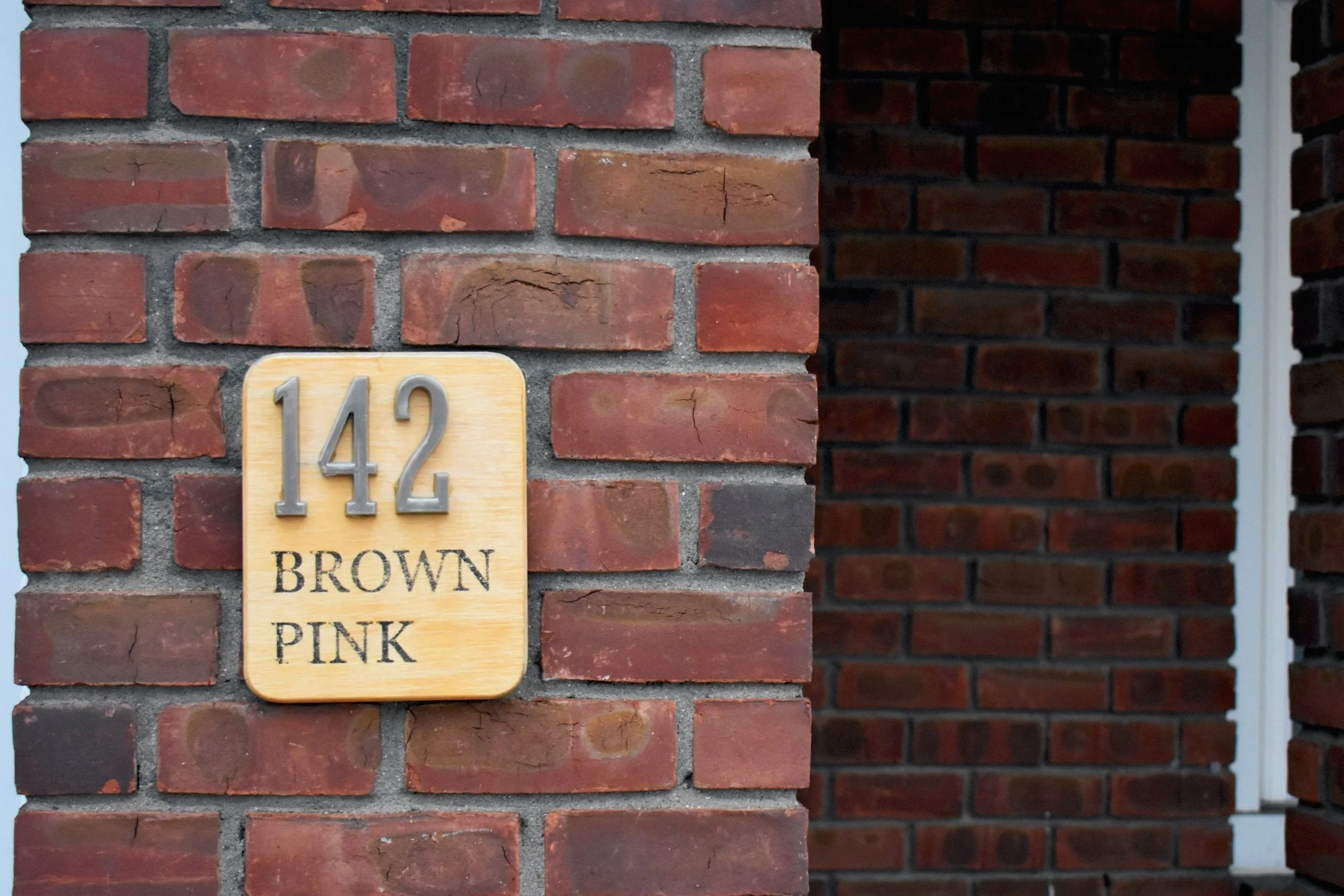 Brick wall with a sign displaying the numbers '142' and the words 'Brown Pink'
