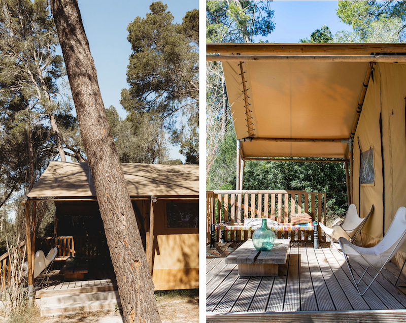 Zeltähnliche Struktur im Wald mit Holzboden und Terrasse, Gartenmöbel und Dekoration, umgeben von Bäumen.