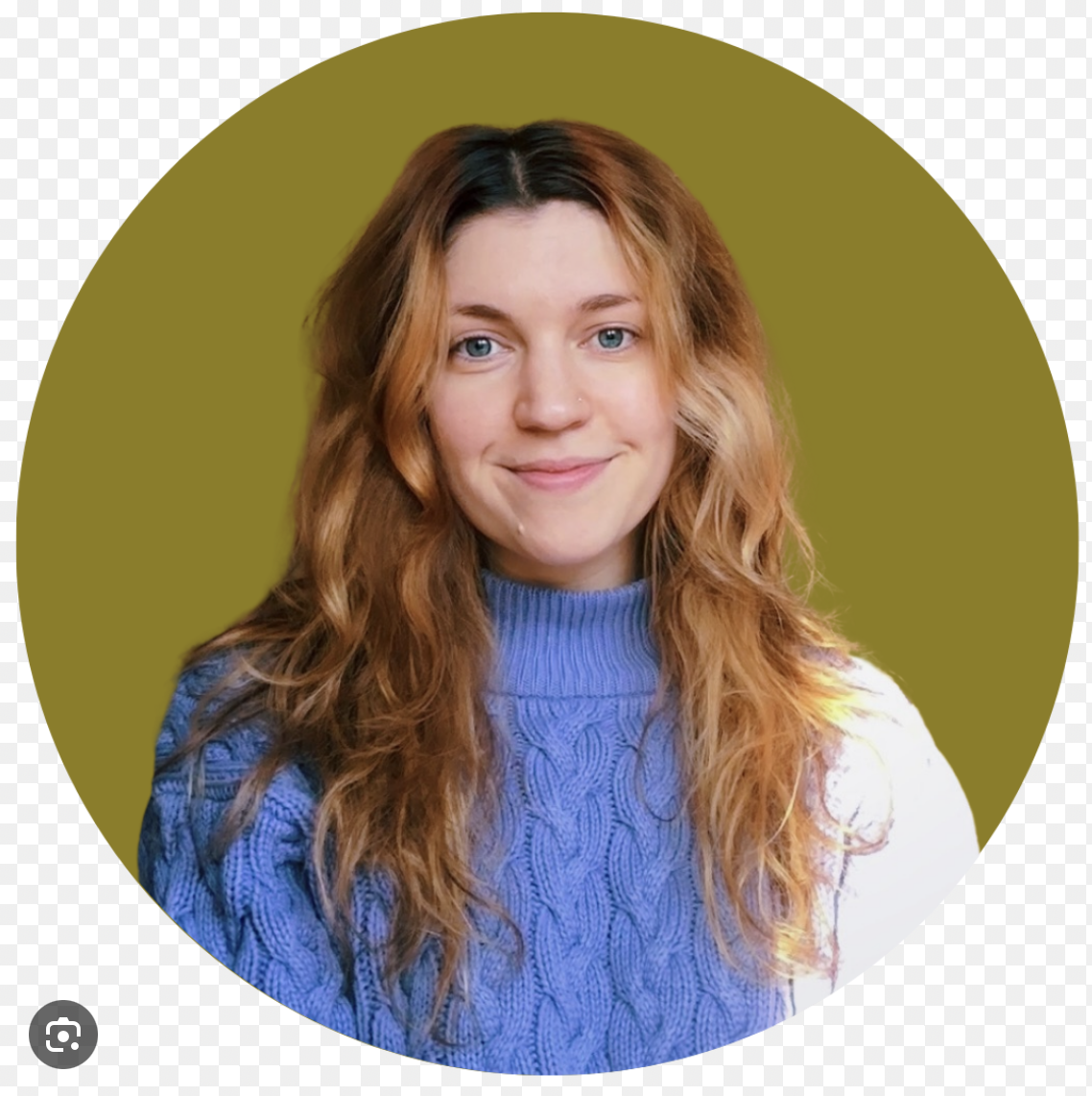 Portrait of Bre Clark, a death doula mentored by Certified Death Doula Jade Adgate through Farewell Fellowship in Nashville, Tennessee. She has long wavy reddish-brown hair, wears a blue knitted sweater, and smiles gently against an olive-green backg