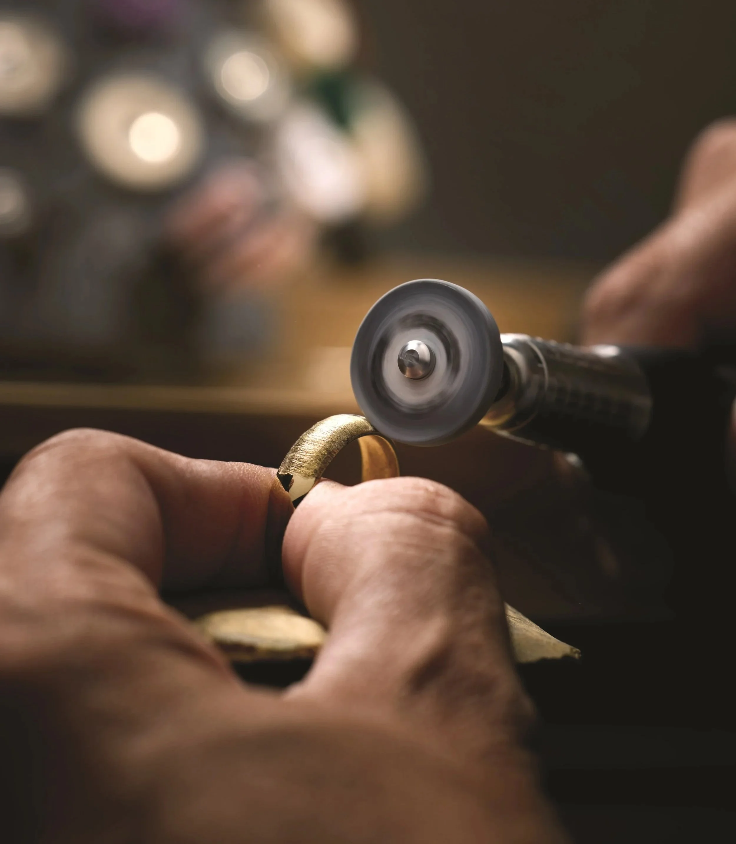 Jeweler polishing a gold ring with a rotating polishing tool.