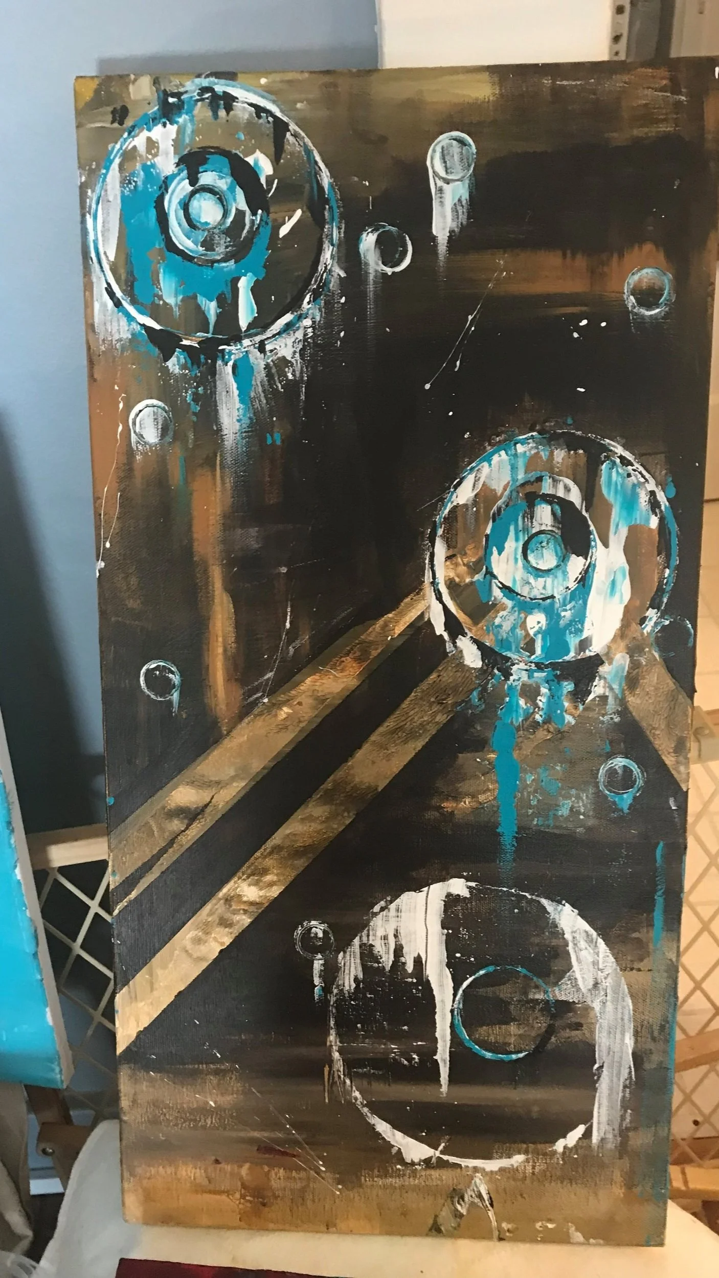 Abstract painting featuring black background with white and blue circular shapes and splatters, some resembling mechanical gears.