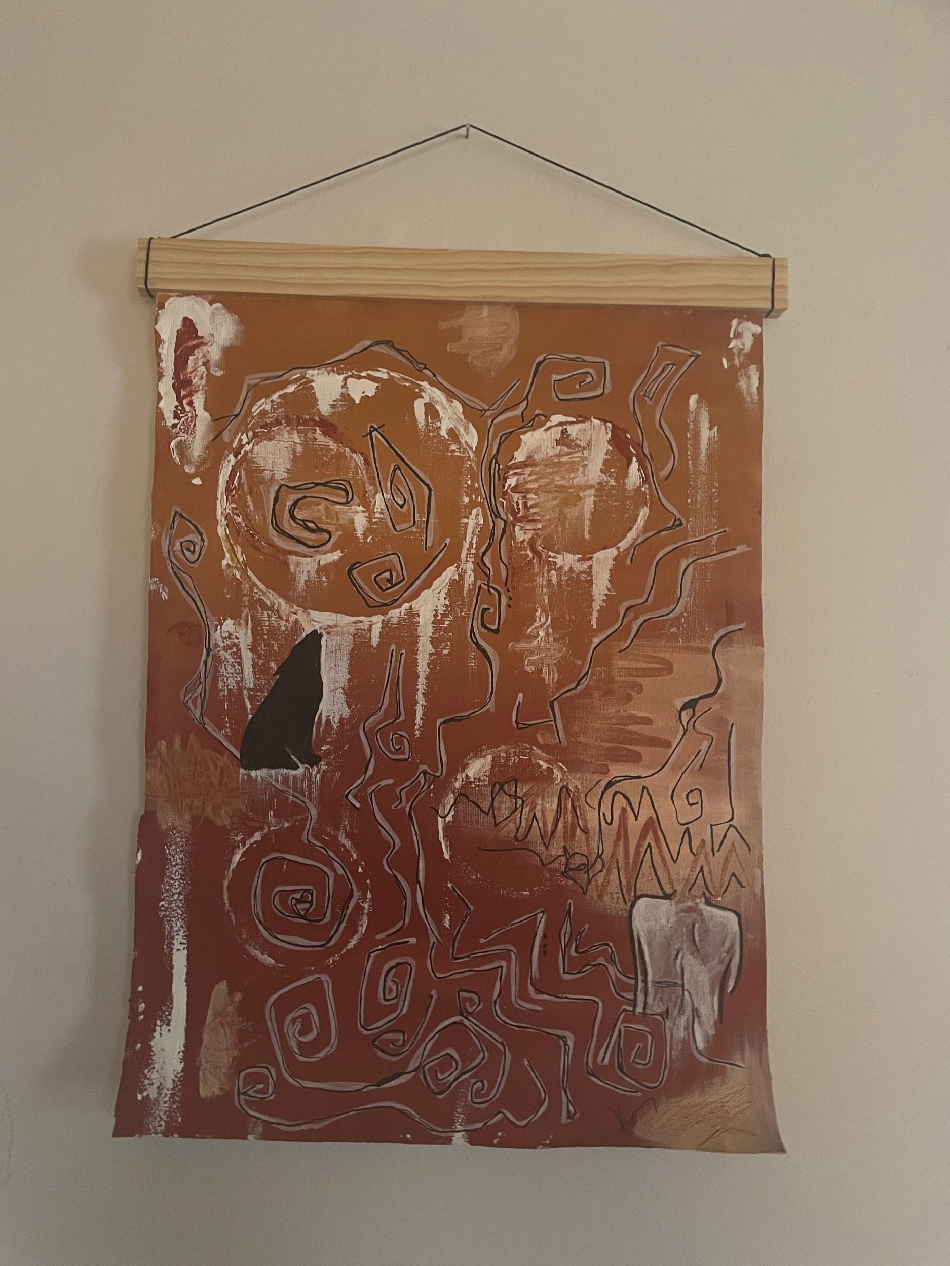 Abstract painting with swirls, lines, and shapes in black, white, and reddish-brown on a rectangular brown canvas, hanging from a wooden dowel with a string.