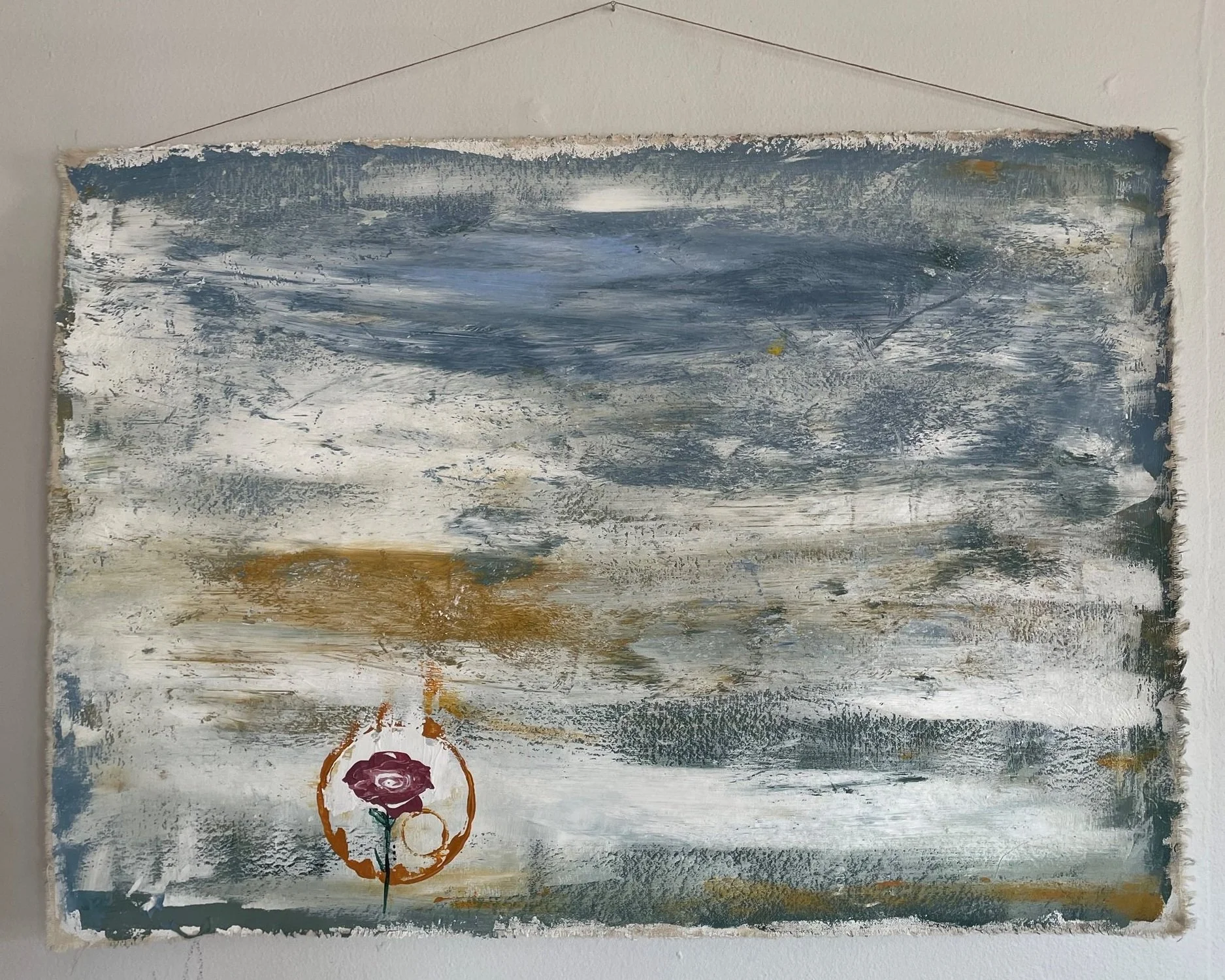 An abstract landscape painting with a cloudy sky in shades of blue, gray, and white, and a bottom section featuring a small circle with a purple flower inside and orange accents.