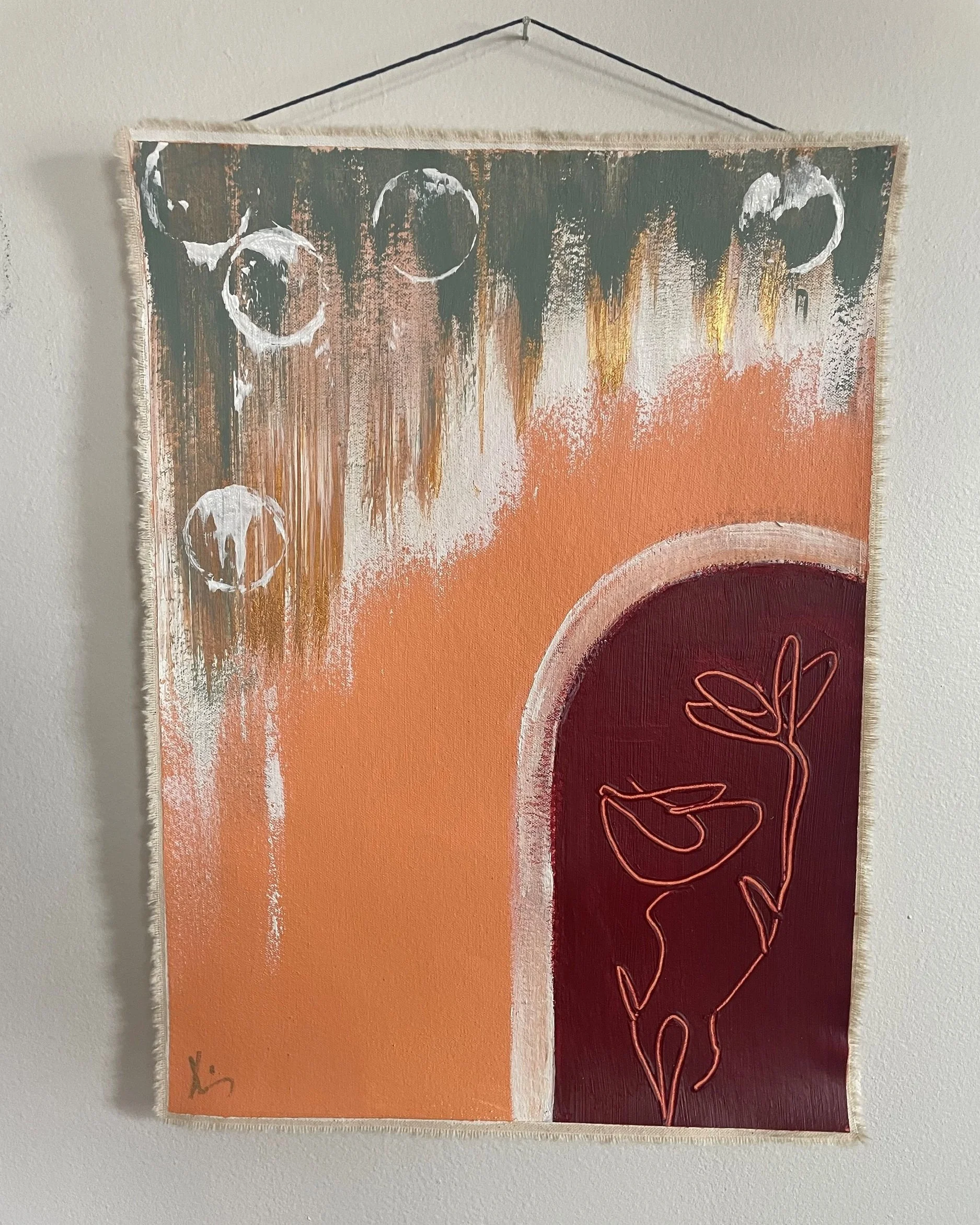 Abstract wall hanging with orange, brown, and white colors and floral line art