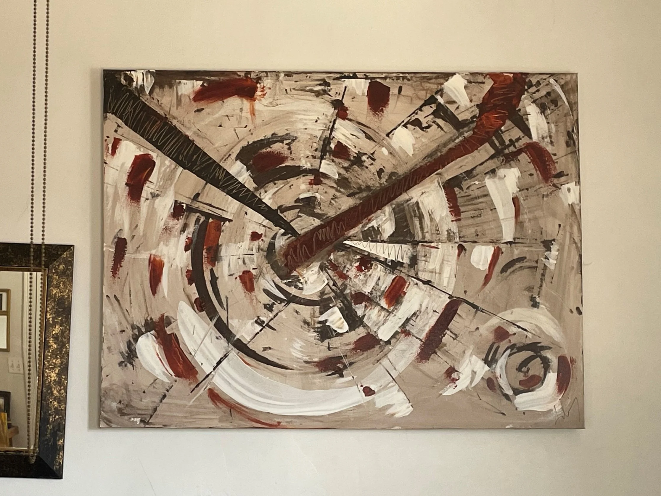 An abstract painting with sweeping strokes and splatters in black, white, red, and brown on a large canvas.