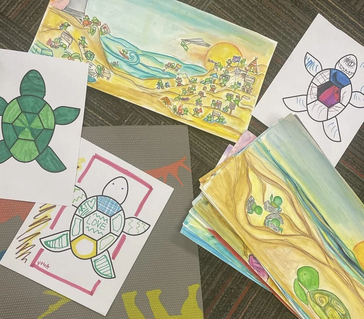 Various children's colored drawings of turtles, a beach scene, and a flower, spread out on a surface.